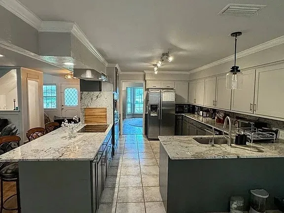 Spacious kitchen featuring an island, peninsula, stainless steel appliances, and tile flooring