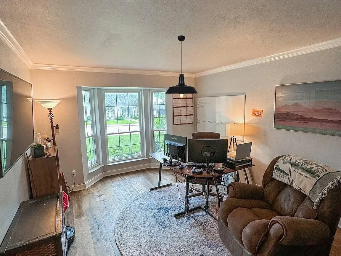 Bay window with multiple panes, crown molding, wood-finish flooring, and a ceiling-mounted light fixture