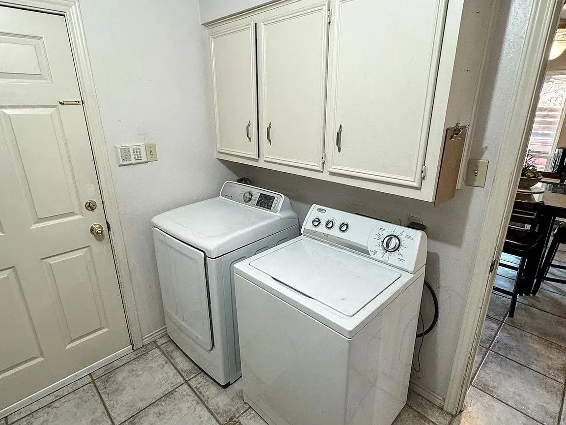 Laundry area featuring overhead cabinetry, a paneled door, and tile flooring