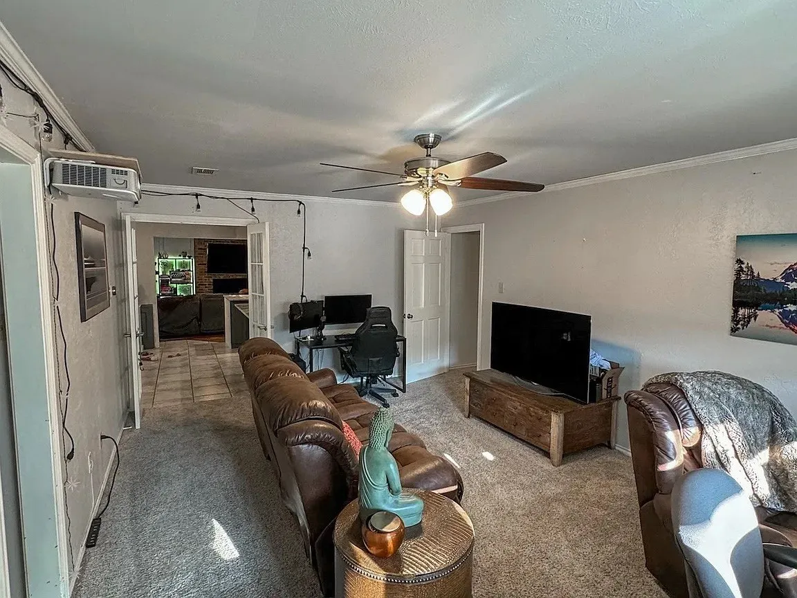Ceiling fan with integrated lighting, crown molding, and a doorway with French doors