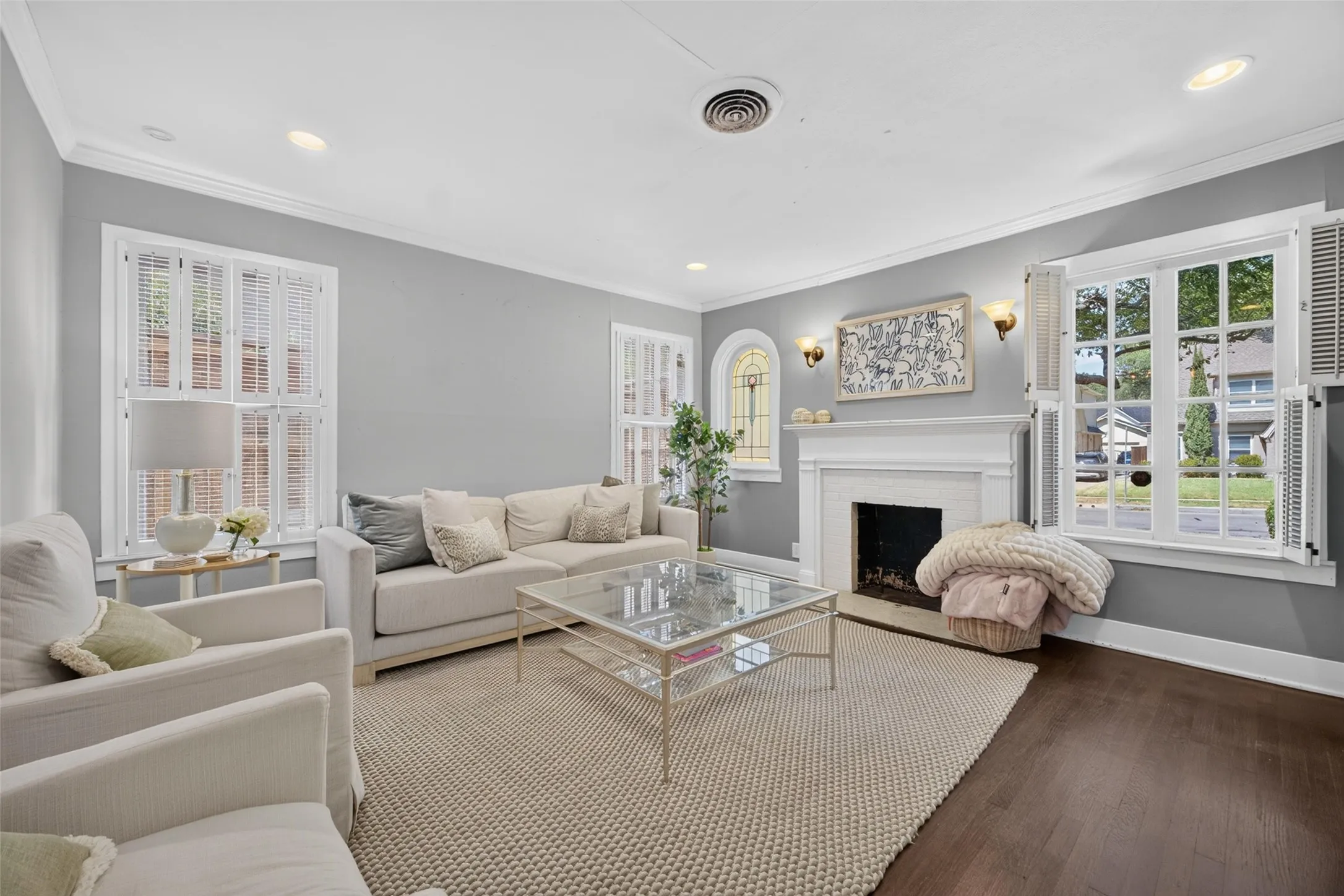 Dark wood-finish flooring, white crown molding, recessed lighting, and a white fireplace mantel