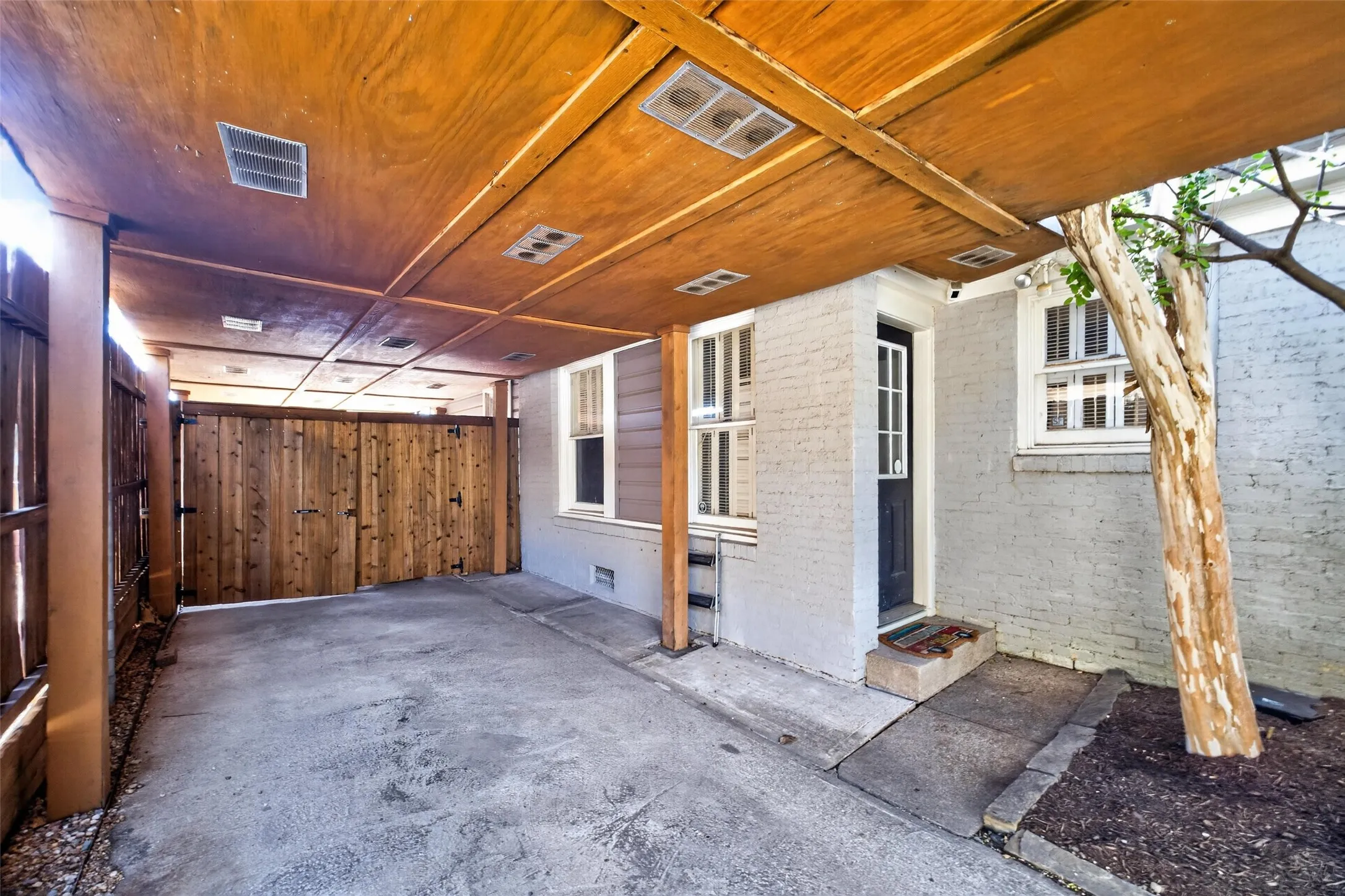 Covered carport featuring a wood-finish ceiling with recessed lighting, concrete flooring, and a privacy gate