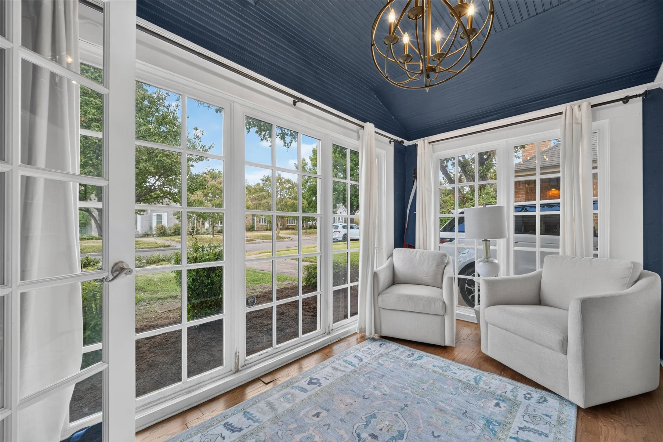 Wood-finish flooring, multiple paneled windows, vaulted ceiling, and an ornate chandelier