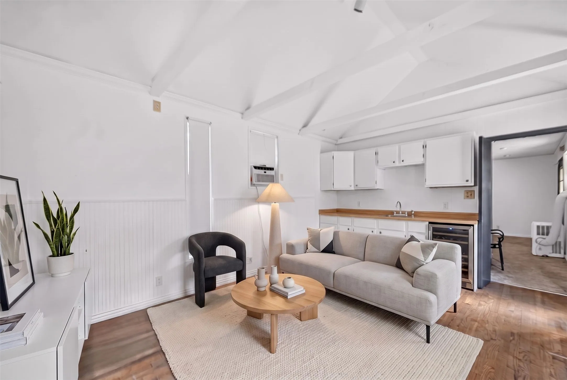 Vaulted beamed ceiling over a kitchenette with white cabinetry, wood-finish countertops, and a built-in beverage refrigerator