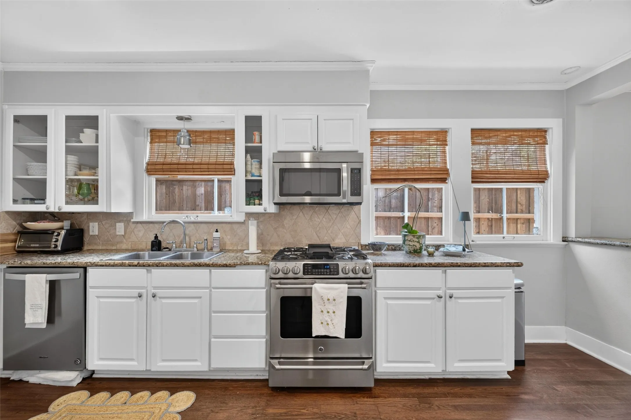 Kitchen featuring white cabinetry, stainless steel appliances, granite countertops, and wood-finish flooring