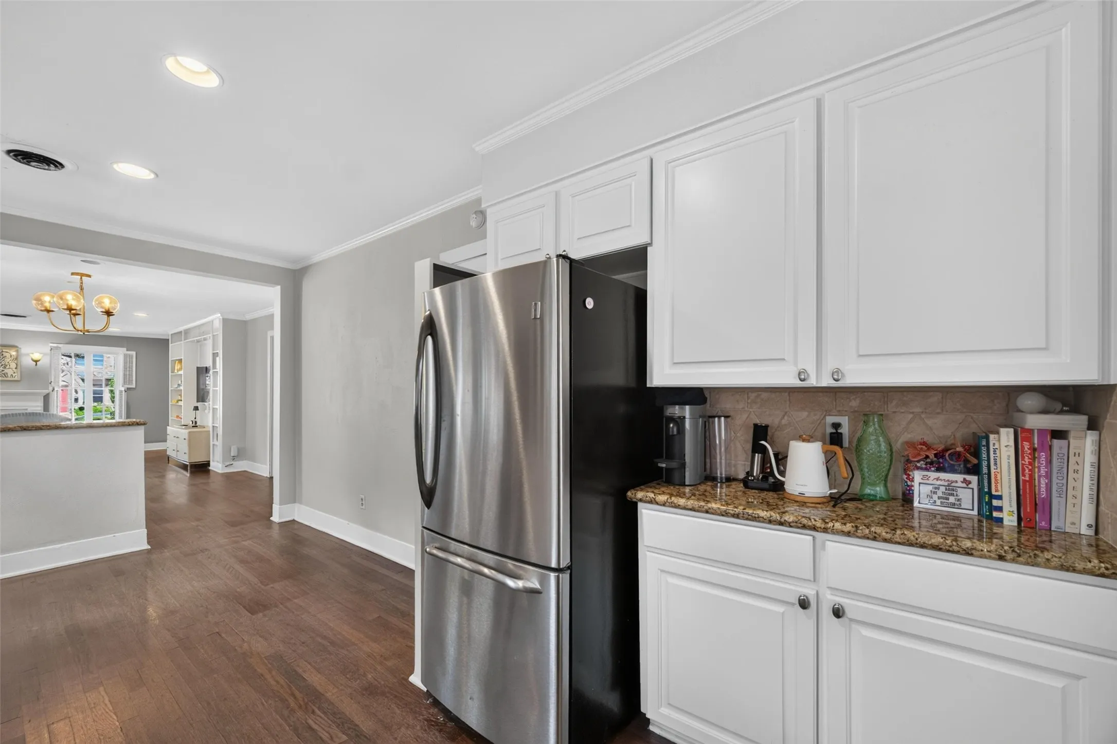 Kitchen with white cabinetry, granite countertops, and stainless steel refrigerator