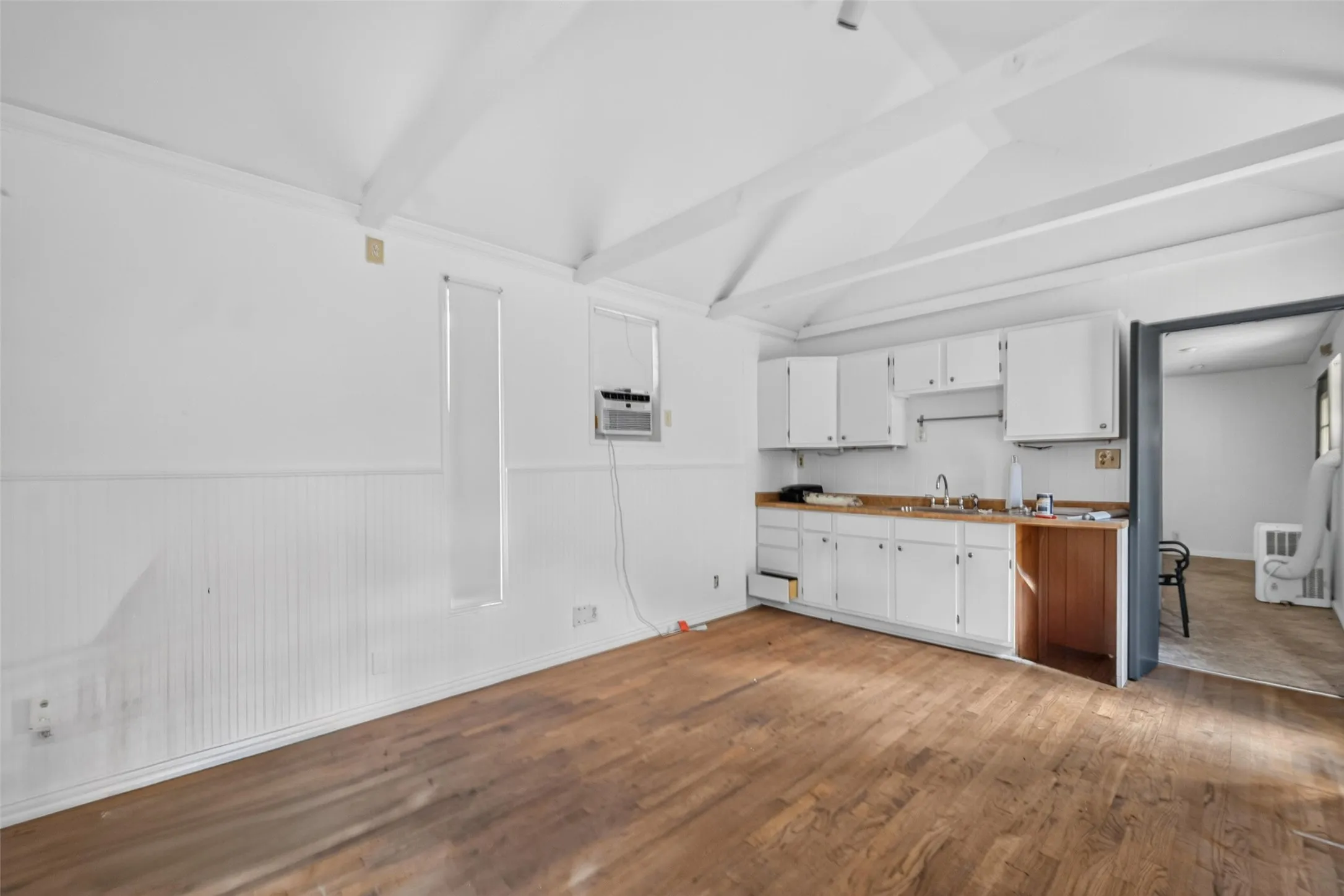 Wood-finish flooring with exposed ceiling beams and beadboard wall paneling