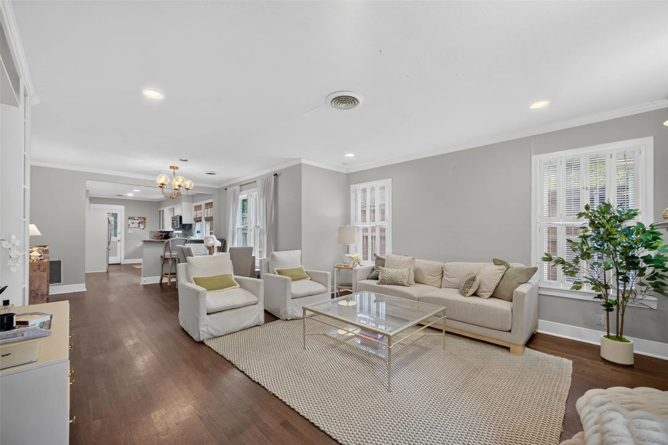 Wood-finish flooring throughout, recessed lighting, crown molding, double windows, and a built-in kitchen island with seating