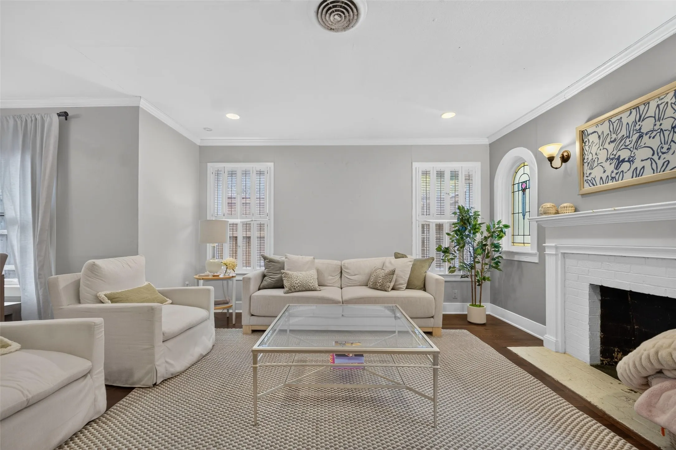Recessed lighting with crown molding, wood-finish flooring, and a fireplace with a white mantel and hearth