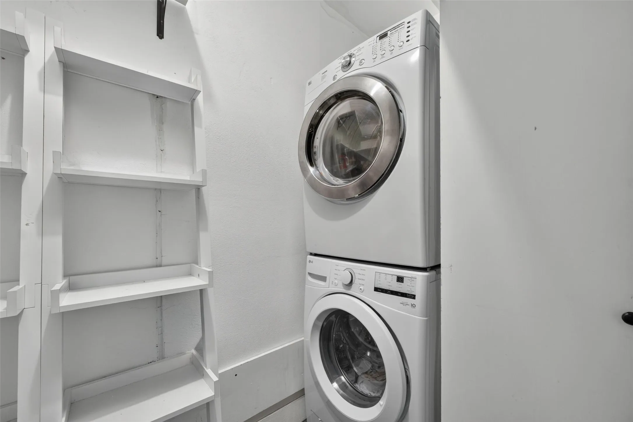 White stacked laundry appliances and white built-in shelving