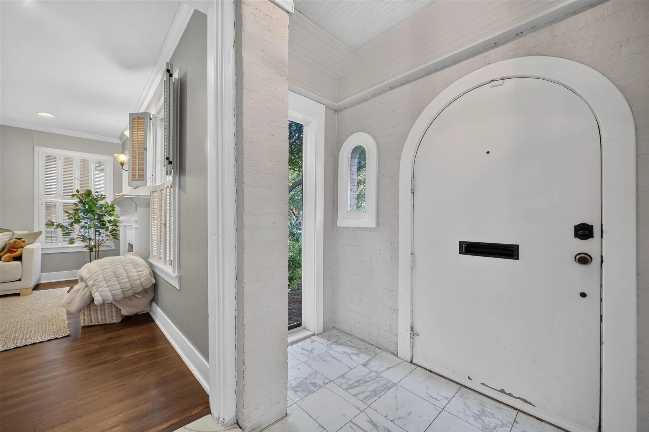 Arched entry door with black hardware, white tile flooring, and an arched window
