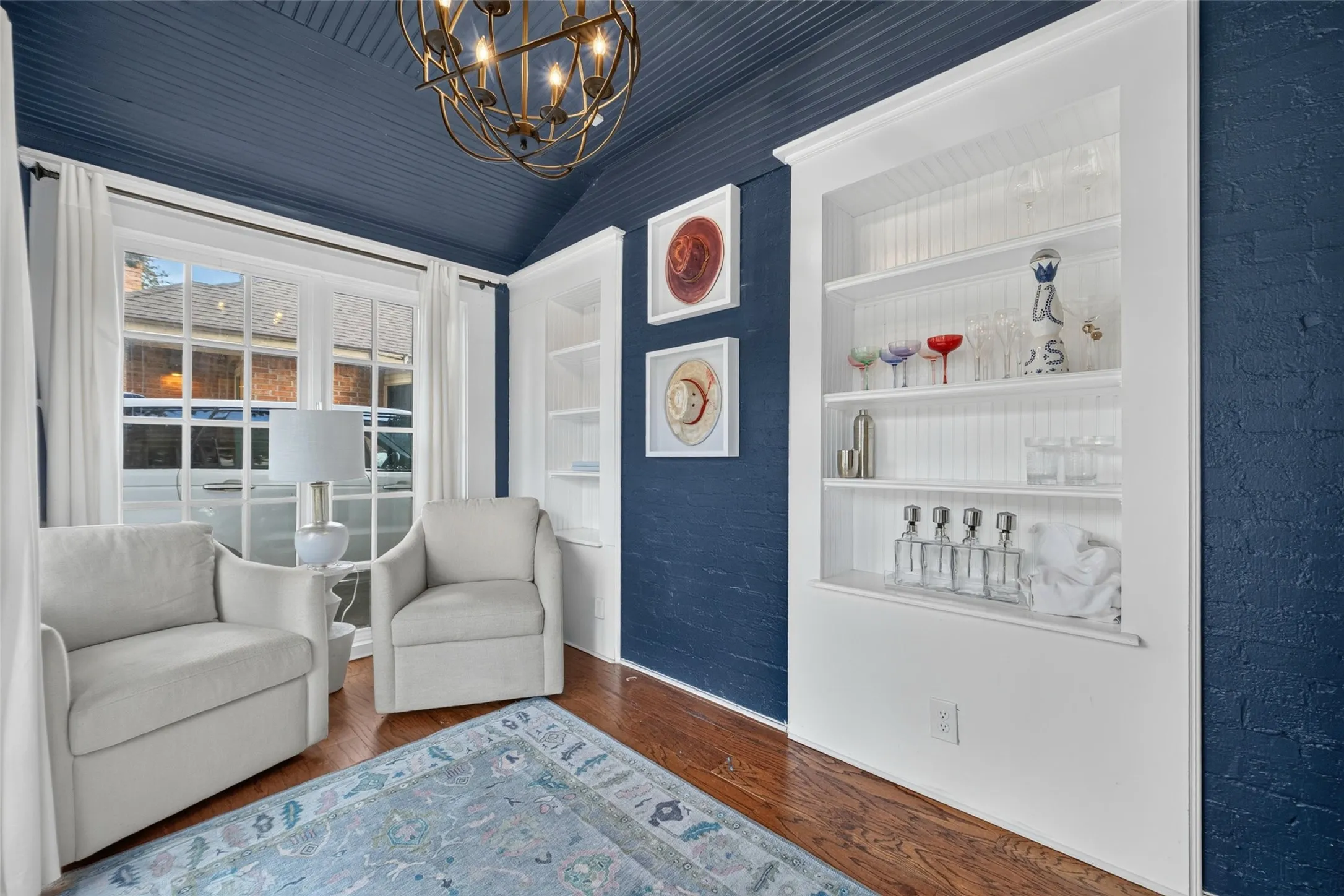 Hardwood flooring, built-in shelving, ornate chandelier, window with grid panes, textured wall finish