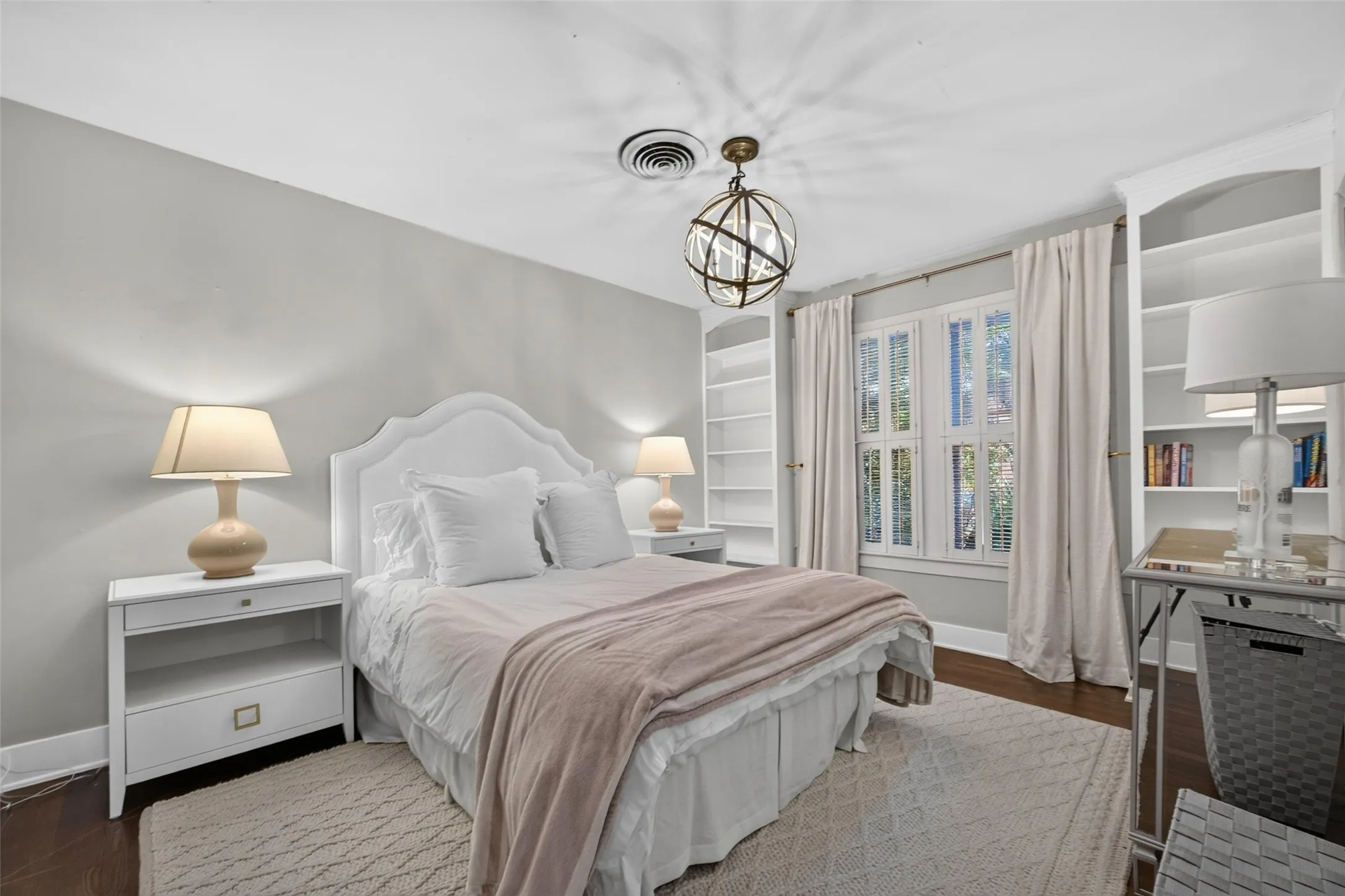 Hardwood flooring, built-in shelving, white window shutters, and a decorative ceiling light fixture