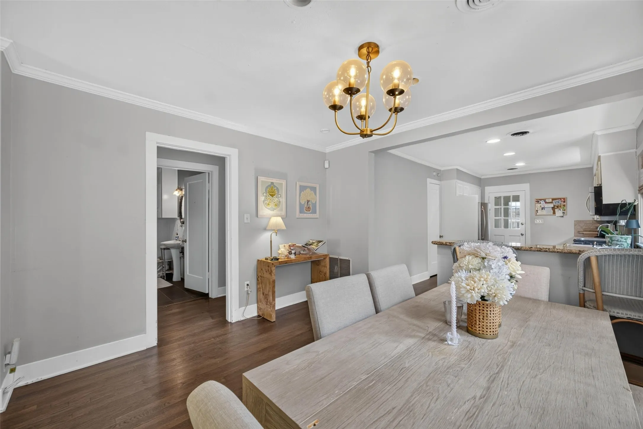 Hardwood flooring, crown molding, cased doorways, recessed lighting, and a brass chandelier