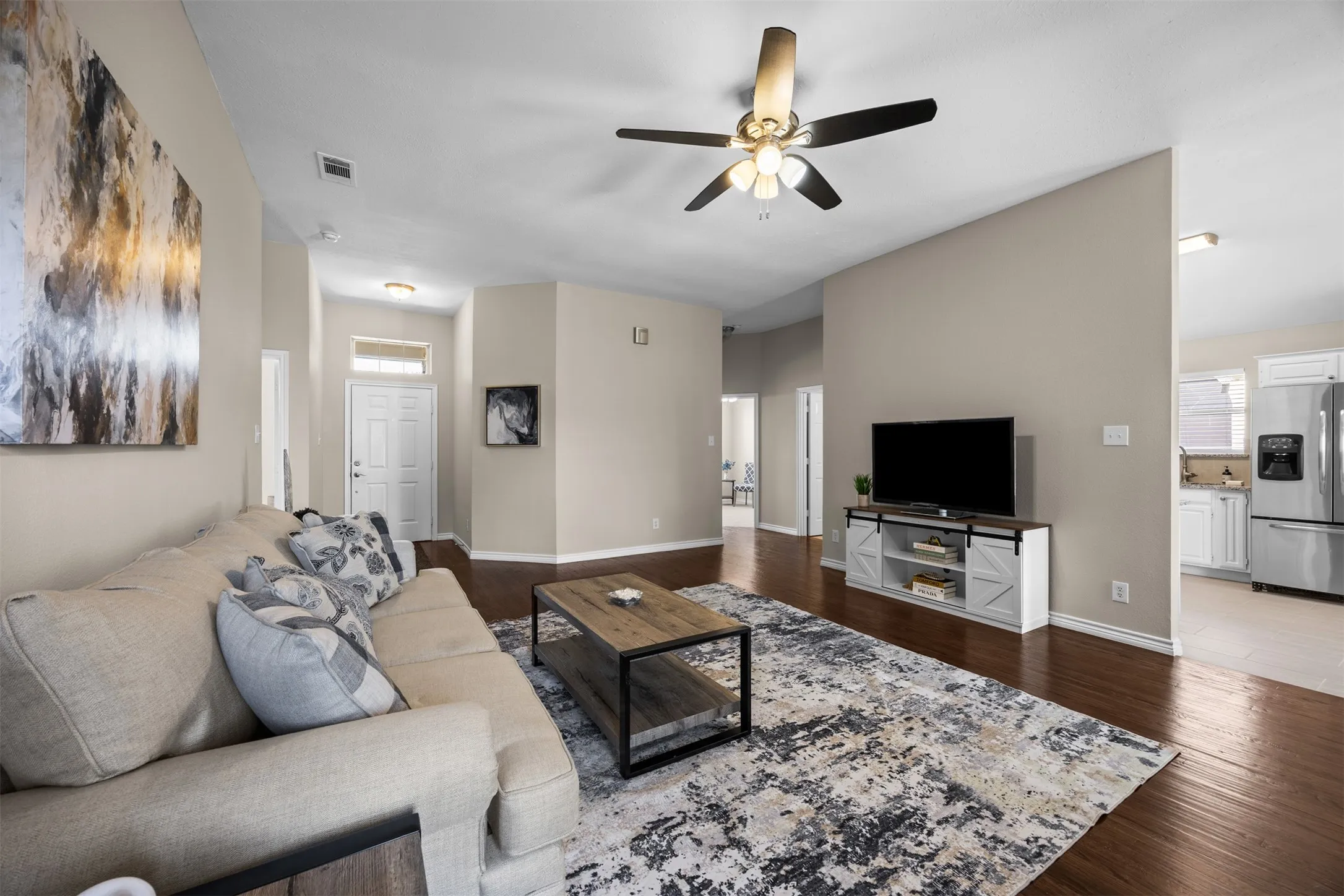 Spacious living room with ceiling fans, fireplace, and hand-scraped wood floors.
