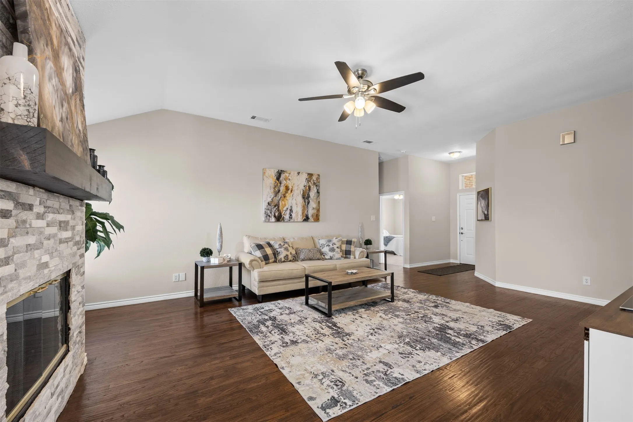 Spacious living room with ceiling fans, fireplace, and hand-scraped wood floors.