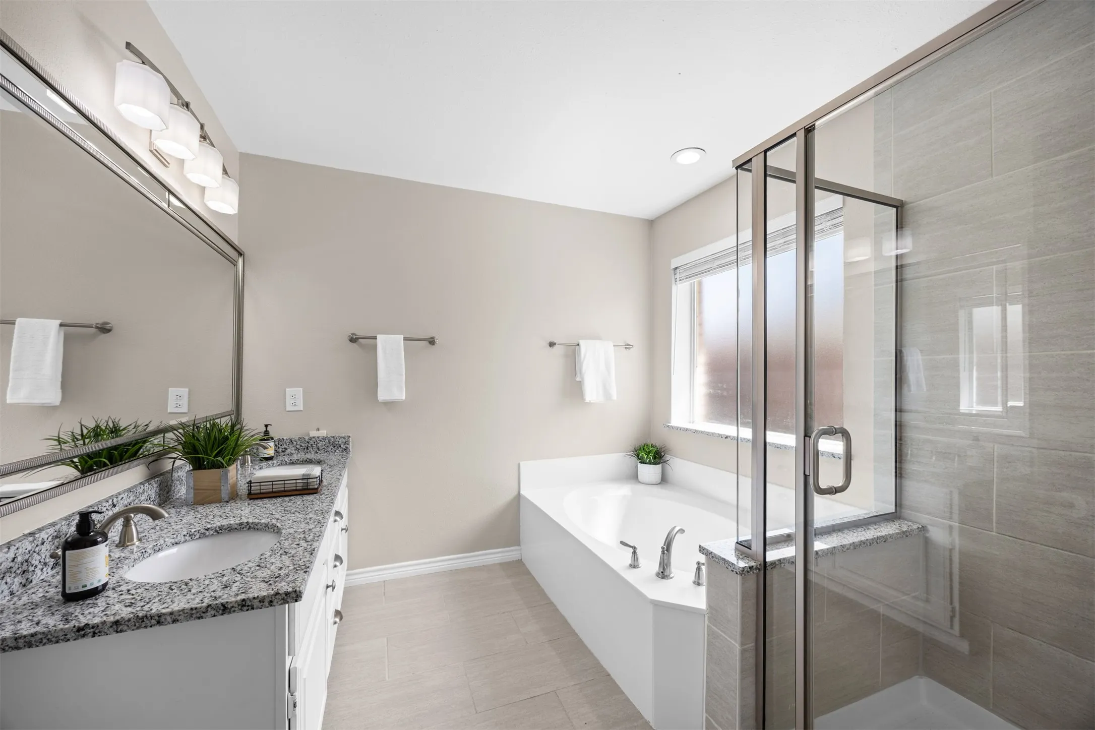Primary ensuite bath with dual vanities, renovated separate shower, and garden tub.