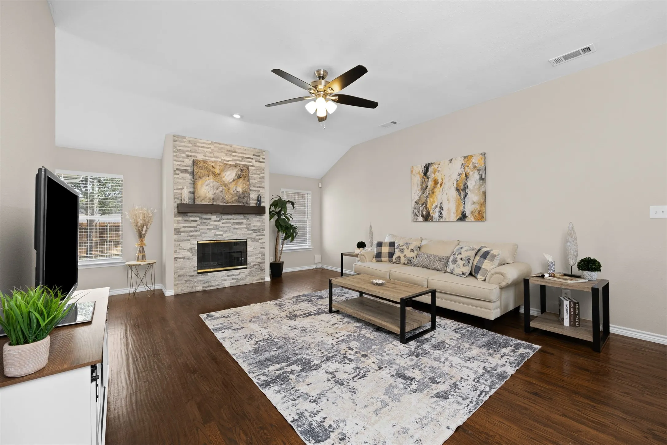 Spacious living room with ceiling fans, fireplace, and hand-scraped wood floors.