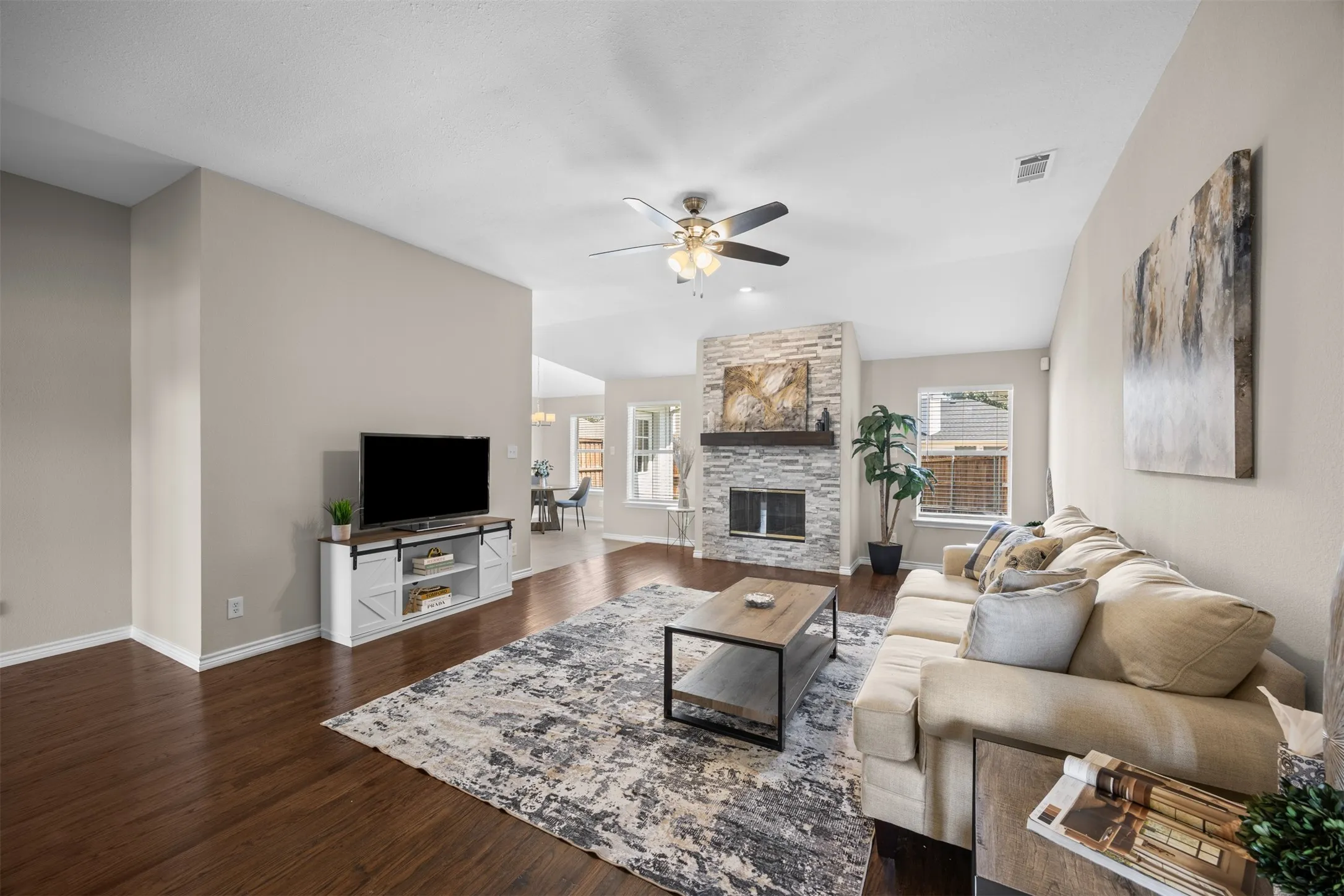Spacious living room with ceiling fans, fireplace, and hand-scraped wood floors.