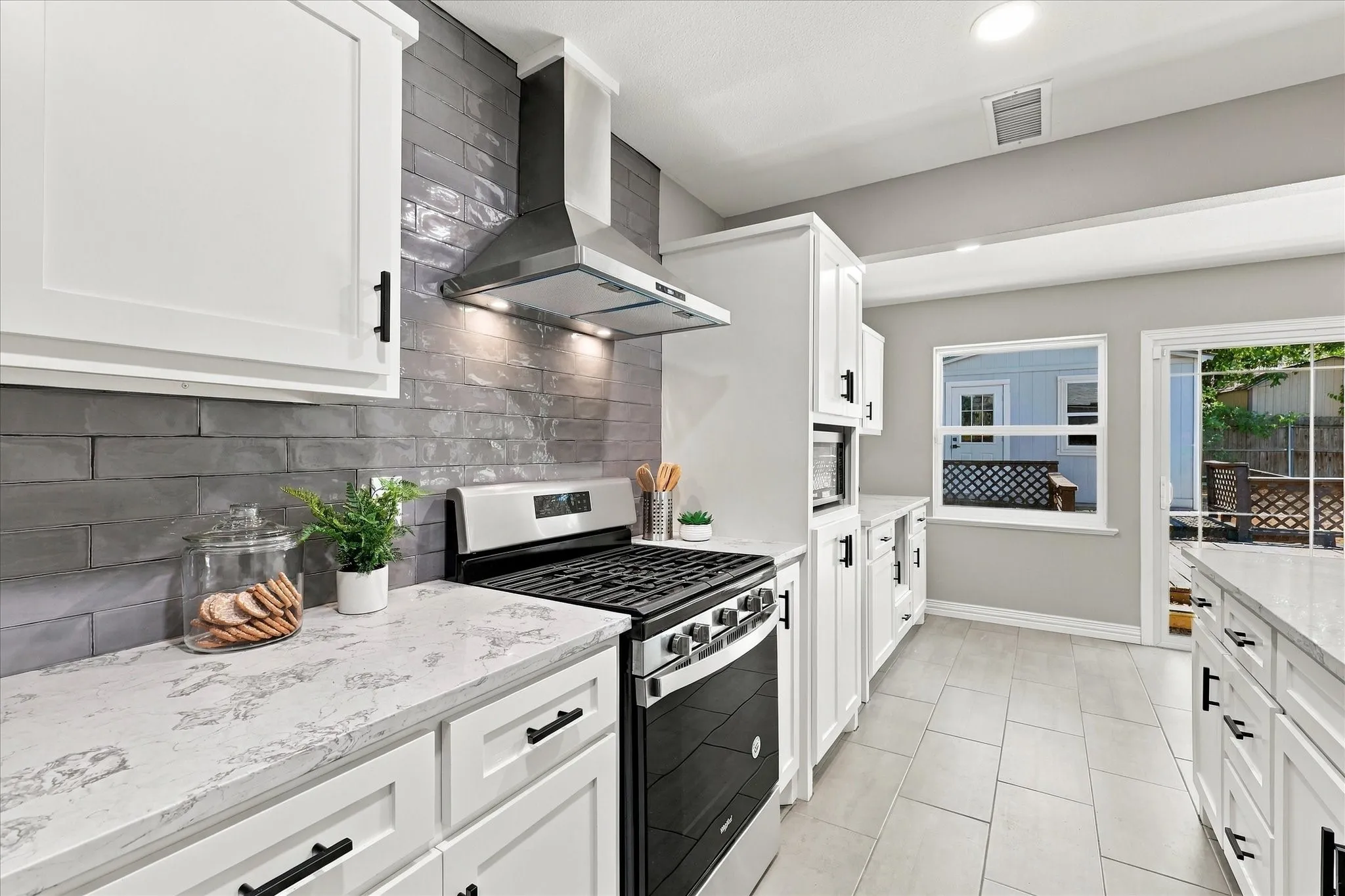 Gorgeous updated kitchen with gas stove, vent hood, stainless appliances, french door fridge, gorgeous backsplash, wine fridge, fully updated cabinetry, and quartz counters