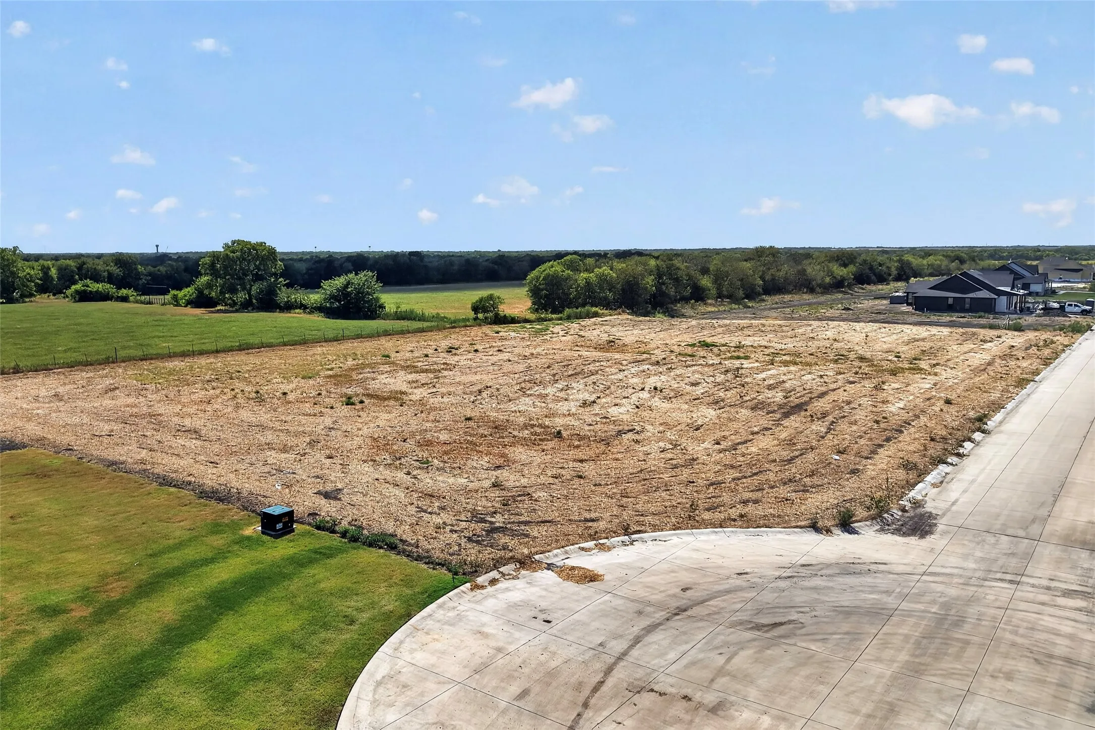 Expansive open lot with a partial paved road.