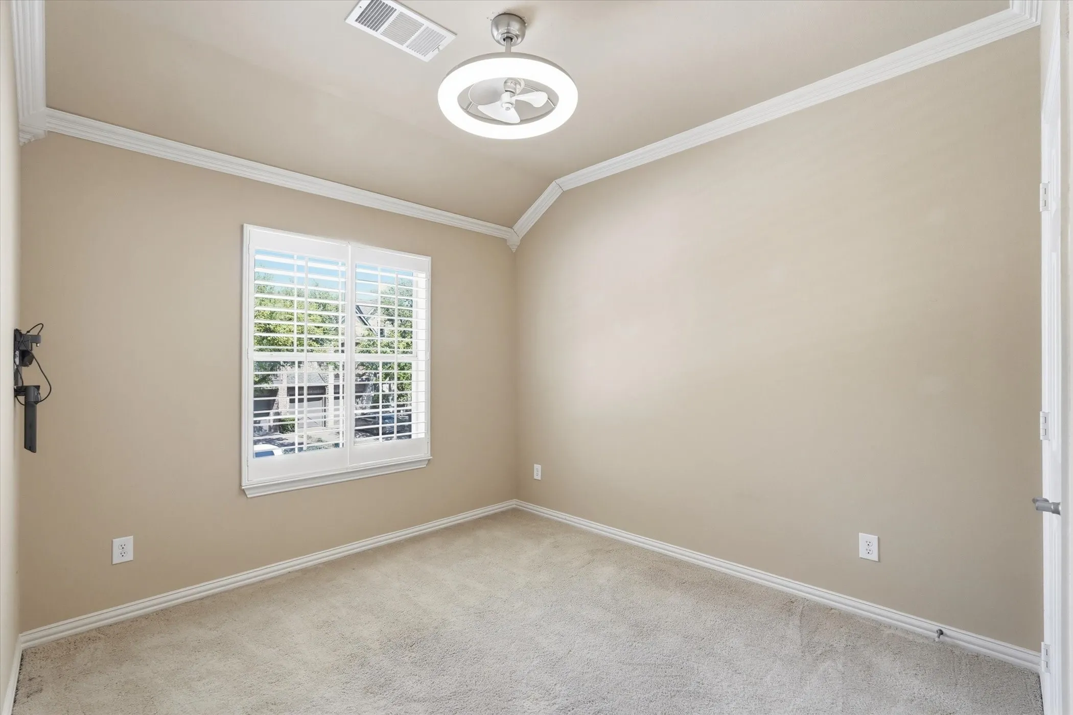 Spare bedroom featuring vaulted ceiling, light colored carpet, and ornamental molding