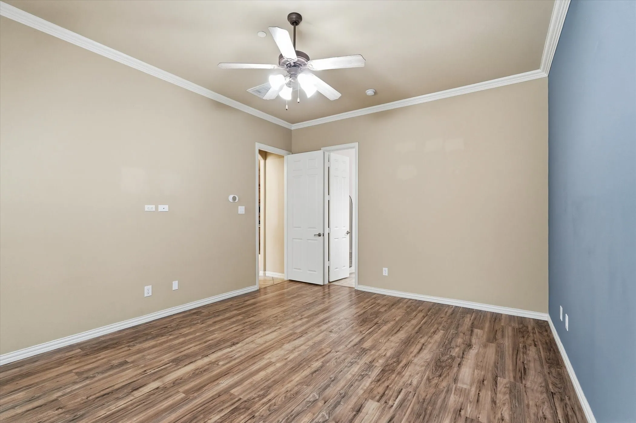Unfurnished bedroom featuring wood finished floors, ornamental molding, and ceiling fan