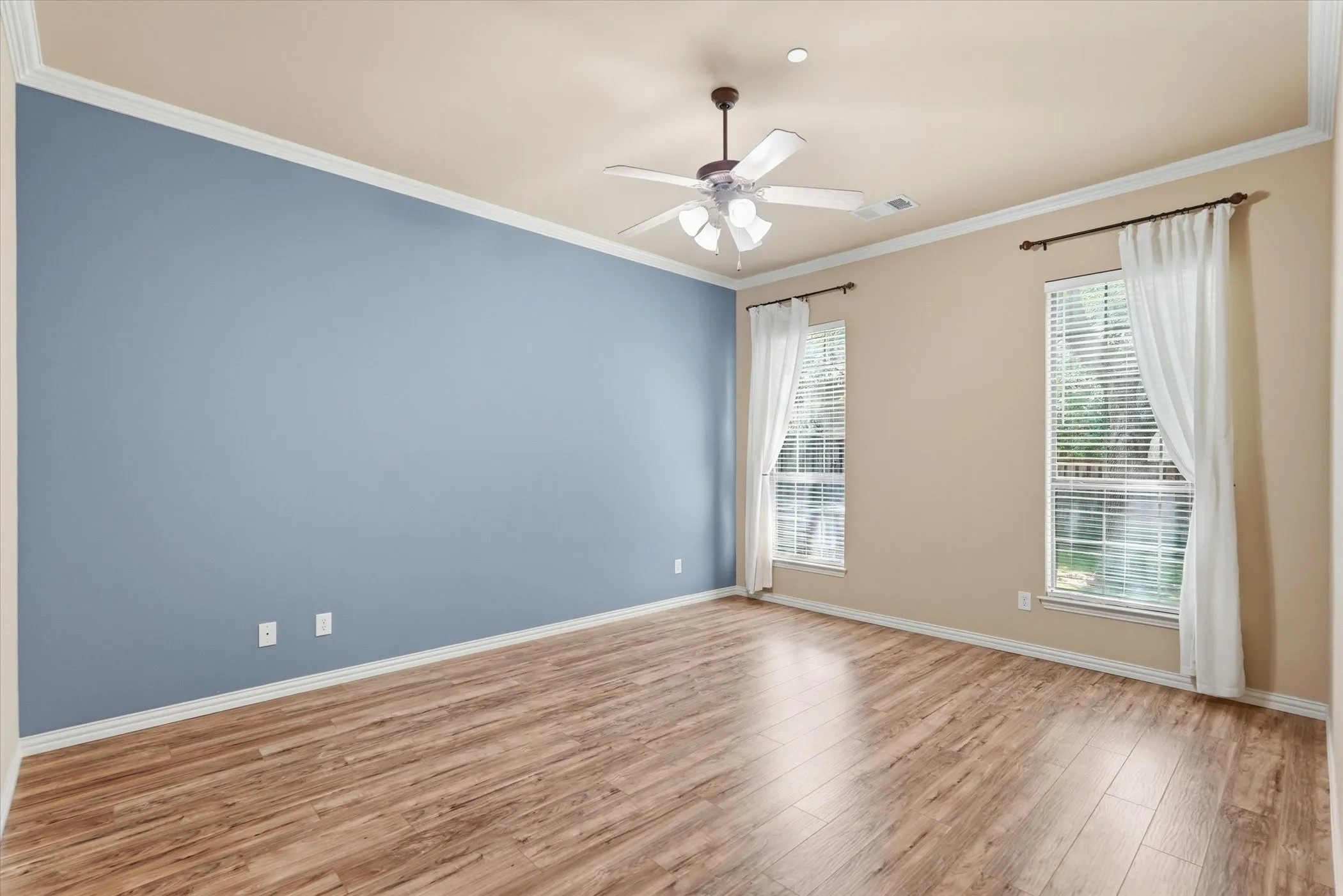 Unfurnished room featuring ceiling fan, light wood-style flooring, and ornamental molding