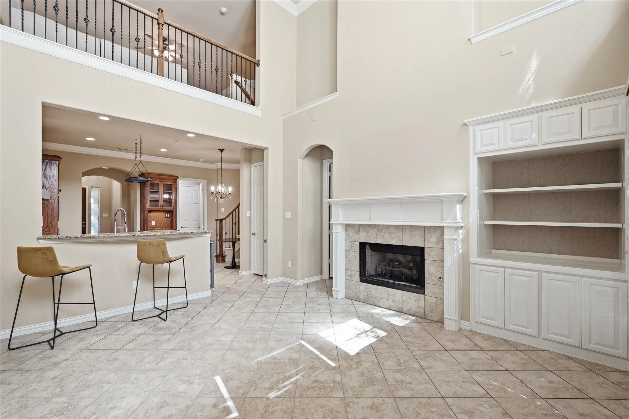 Unfurnished living room with ornamental molding, a high ceiling, hanging lights, arched walkways, and a fireplace