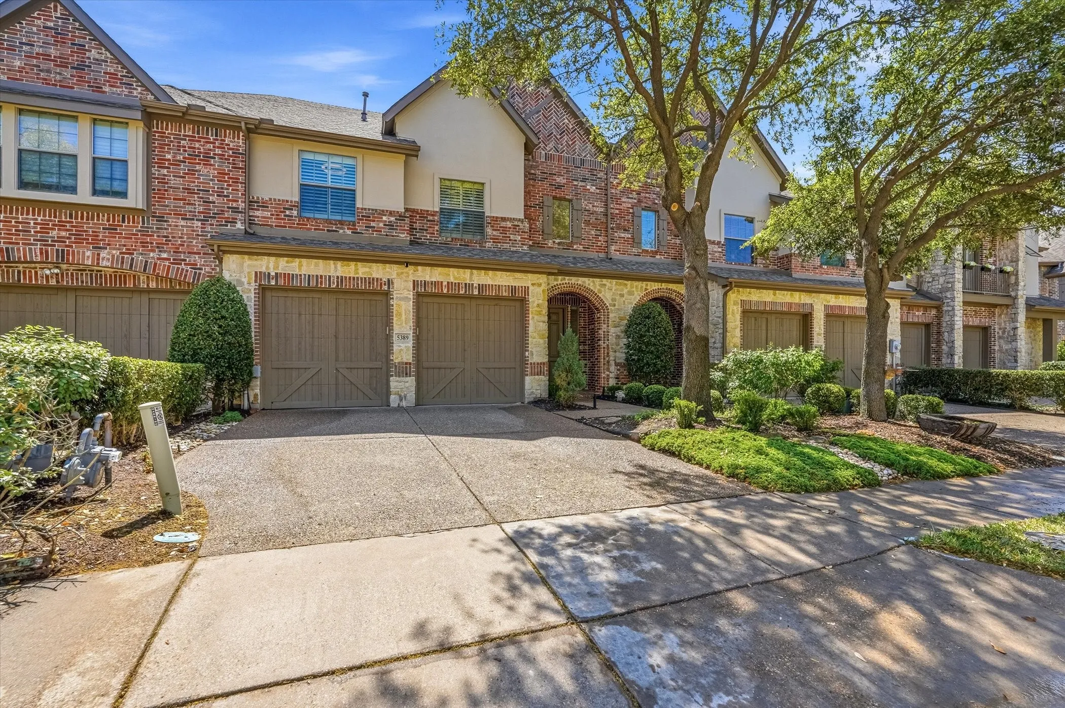 Traditional-style home featuring brick siding, driveway, stucco siding, and a garage