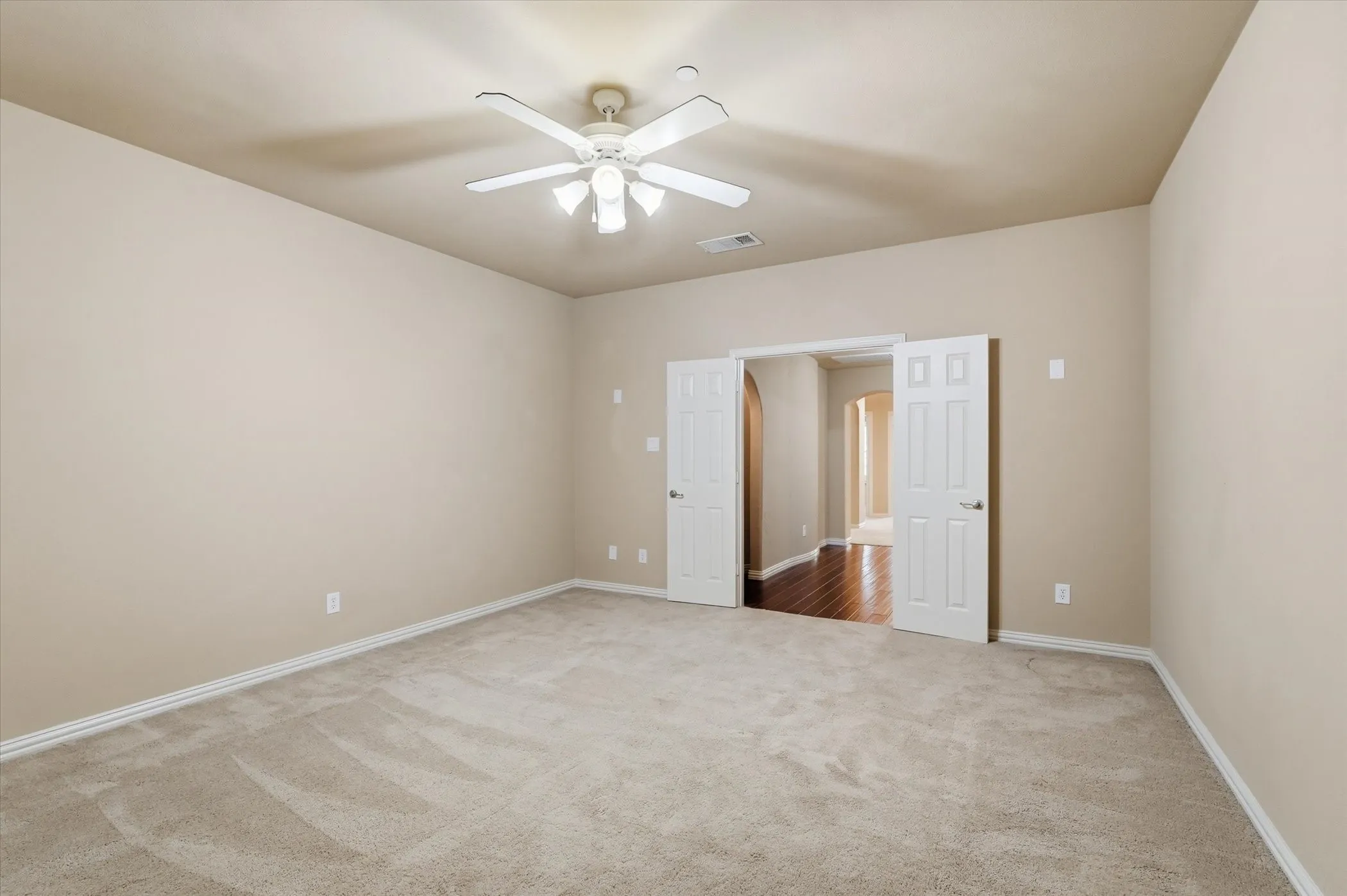 Empty room with light colored carpet and ceiling fan