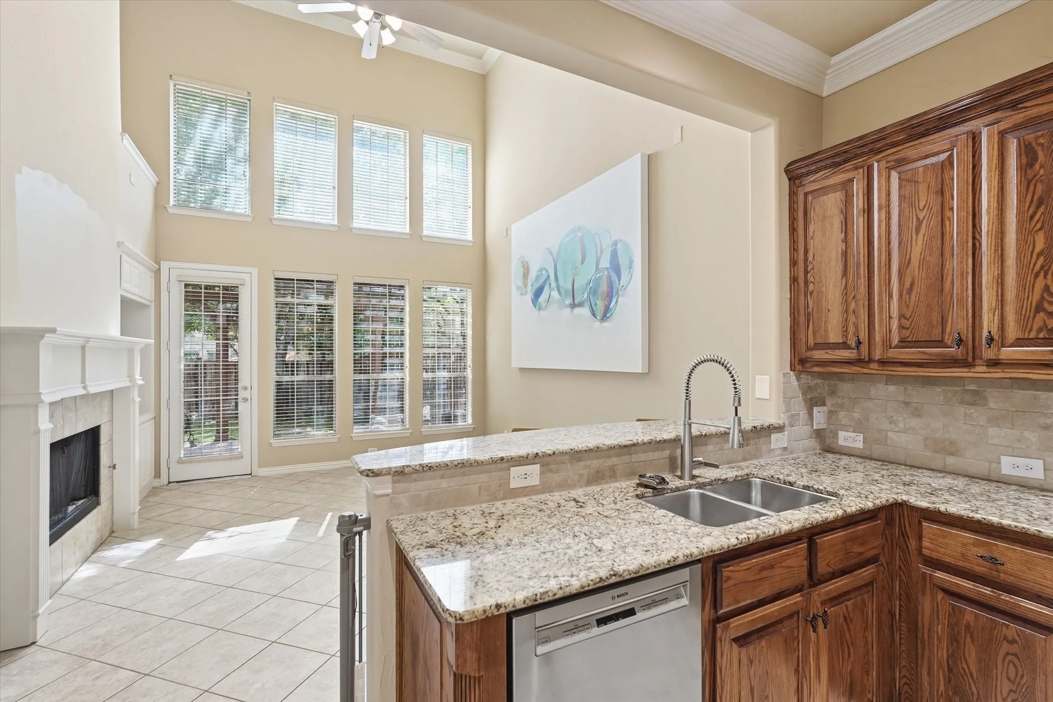 Kitchen with wood finish cabinets, dishwasher, a peninsula, light stone counters, and light tile patterned​​‌​​​​‌​​‌‌​‌‌​​​‌‌​‌​‌​‌​​​‌​​ flooring