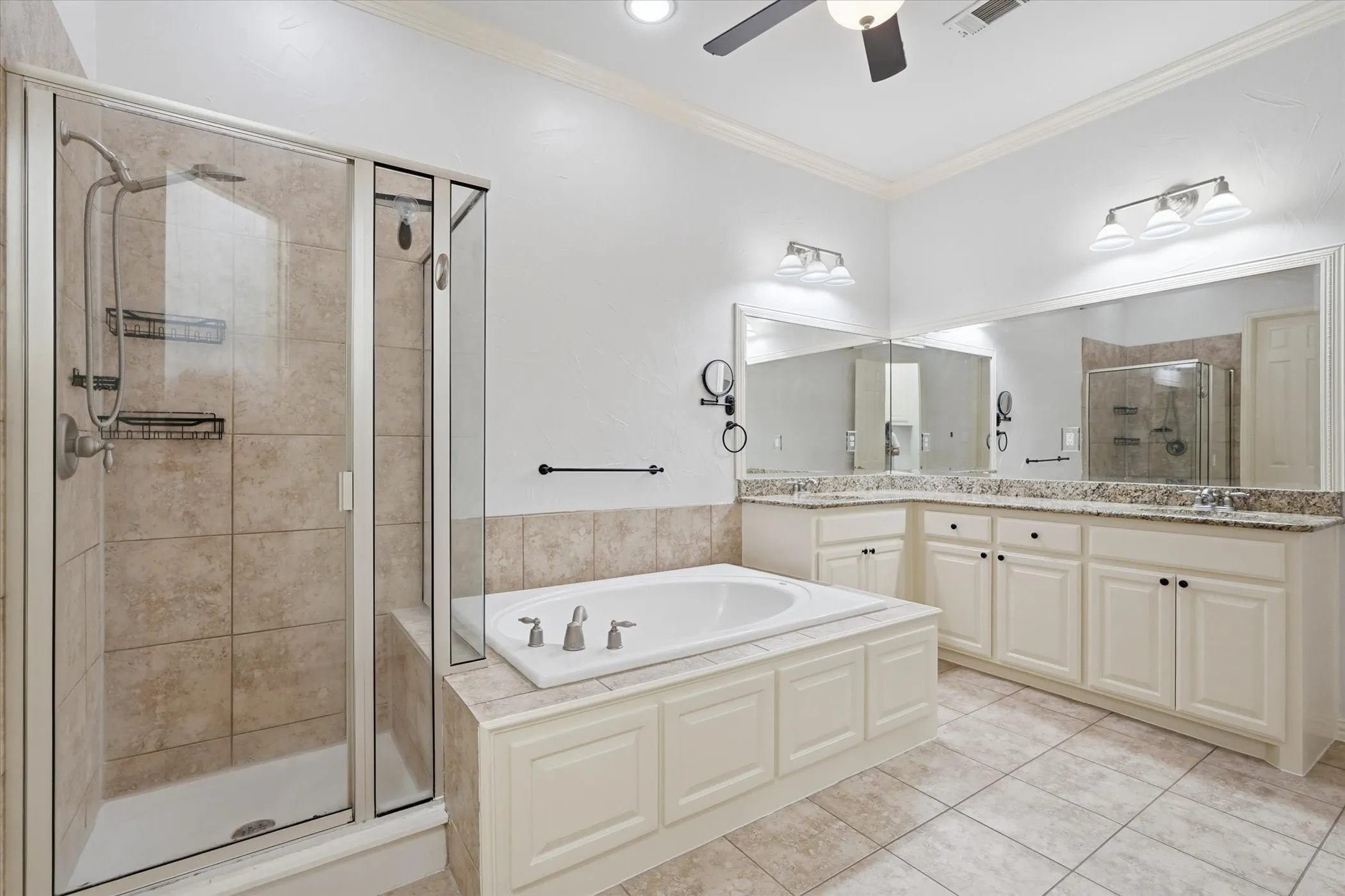 Bathroom featuring double vanity, a stall shower, a bath, crown molding, and ceiling fan