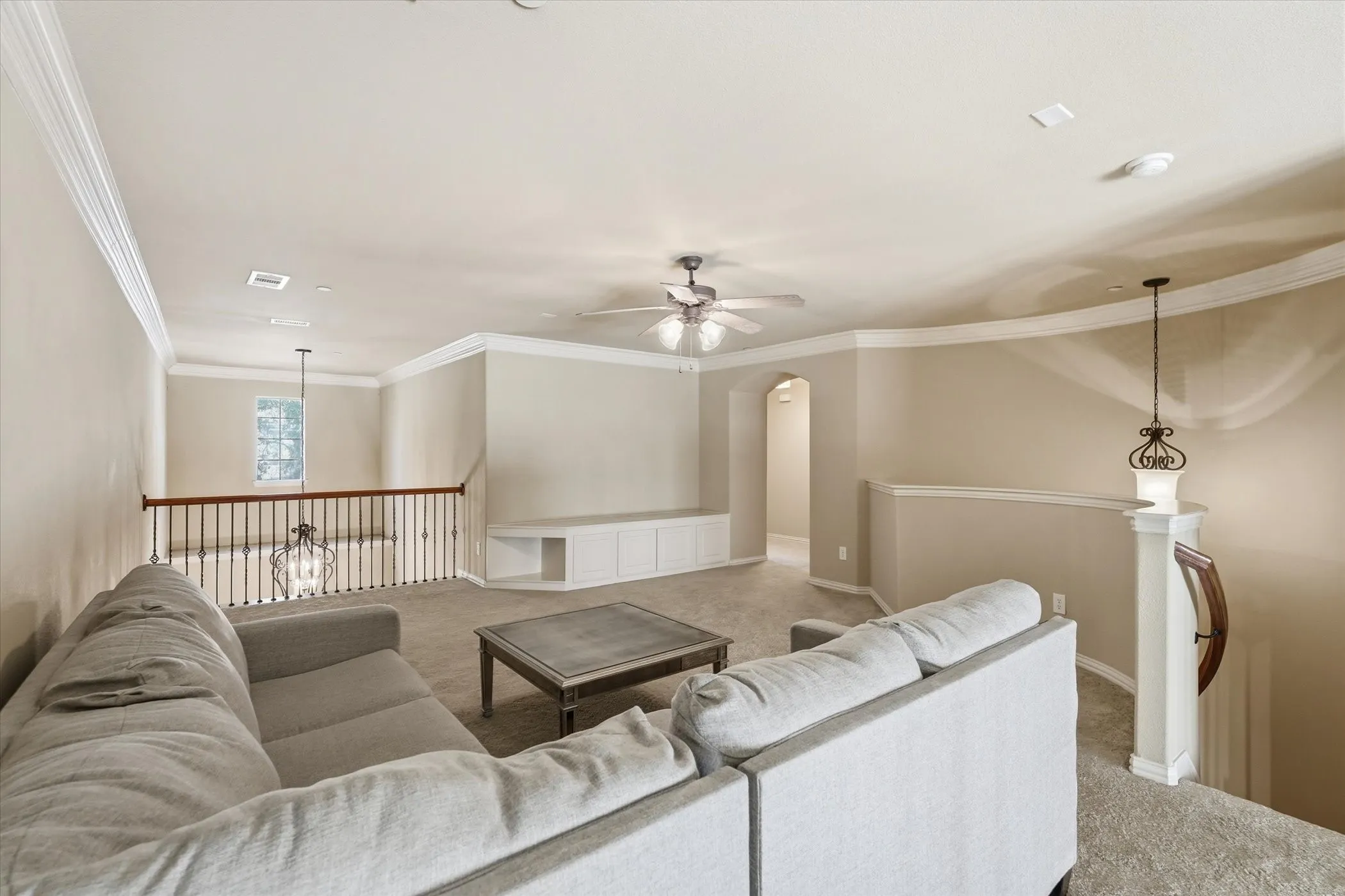 Upstairs Living room featuring light colored carpet, ceiling fan, arched walkways, and ornamental molding