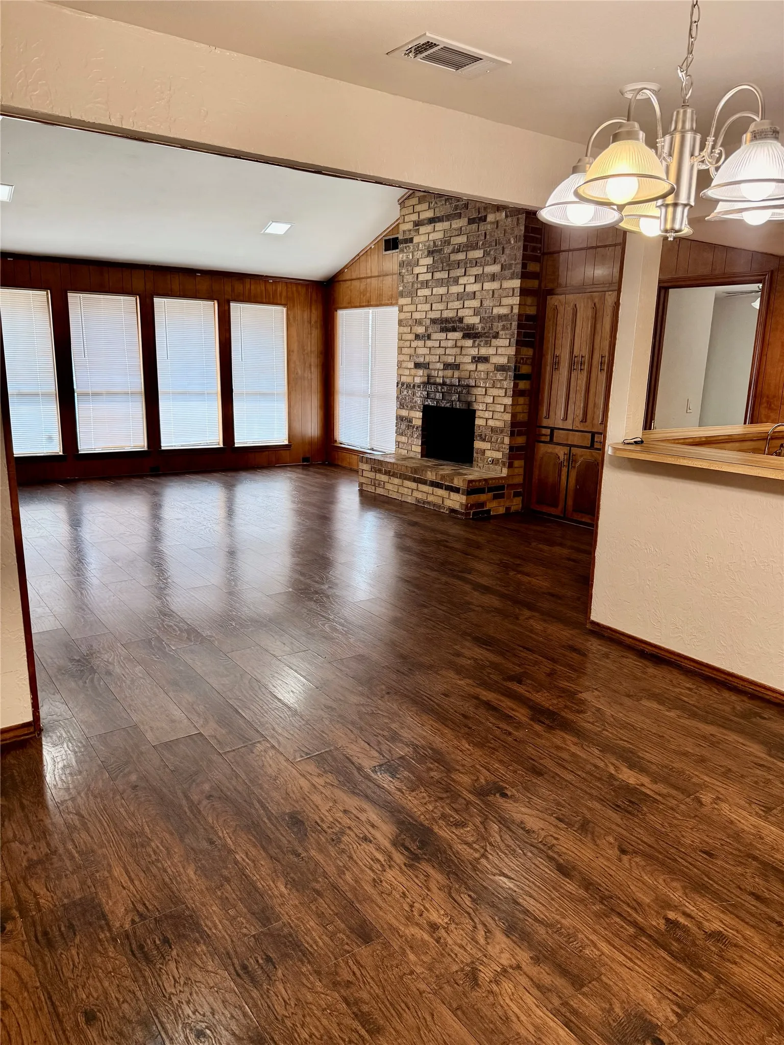 Open living area with fireplace, wall of windows and vaulted ceiling.