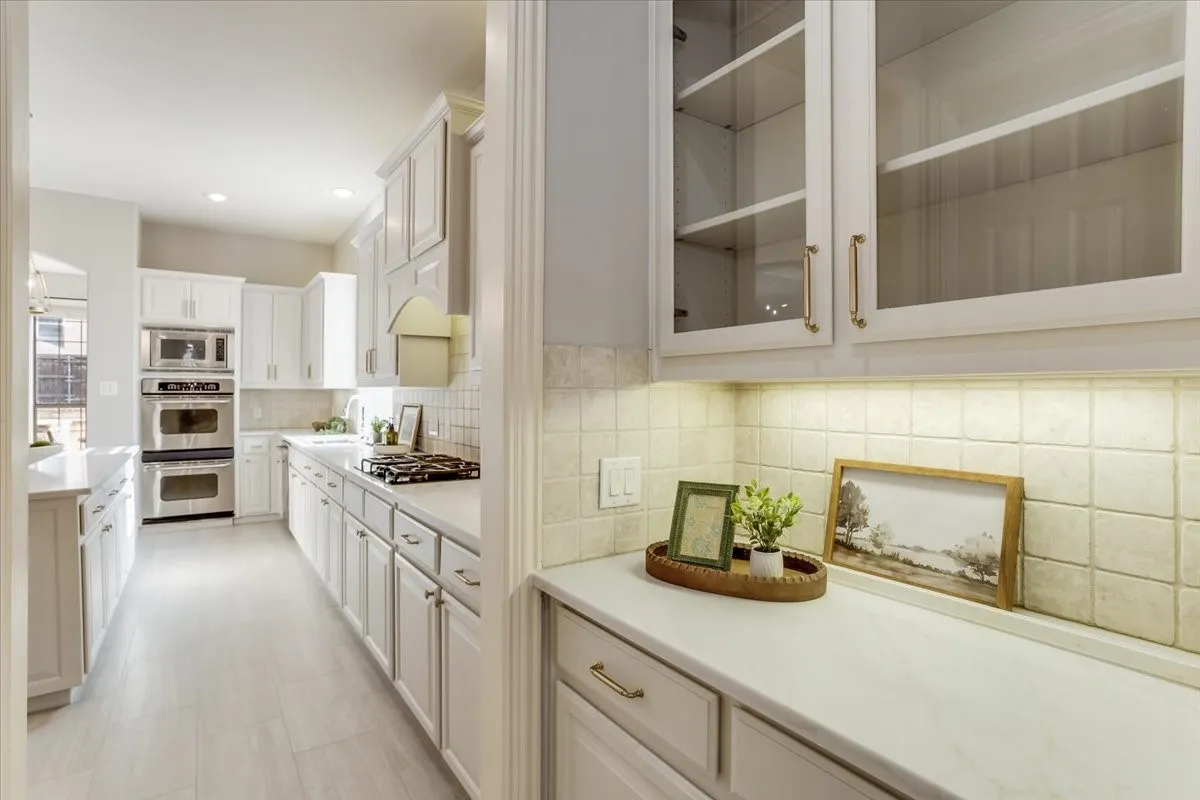 Kitchen featuring light-finish cabinetry, stainless steel double ovens, a gas cooktop, tile backsplash, and light-toned countertops