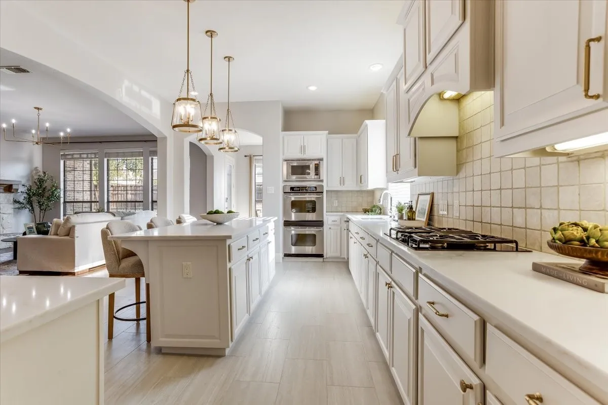 Kitchen featuring a center island, pendant lighting, stainless steel double ovens, a gas cooktop, and a tile backsplash