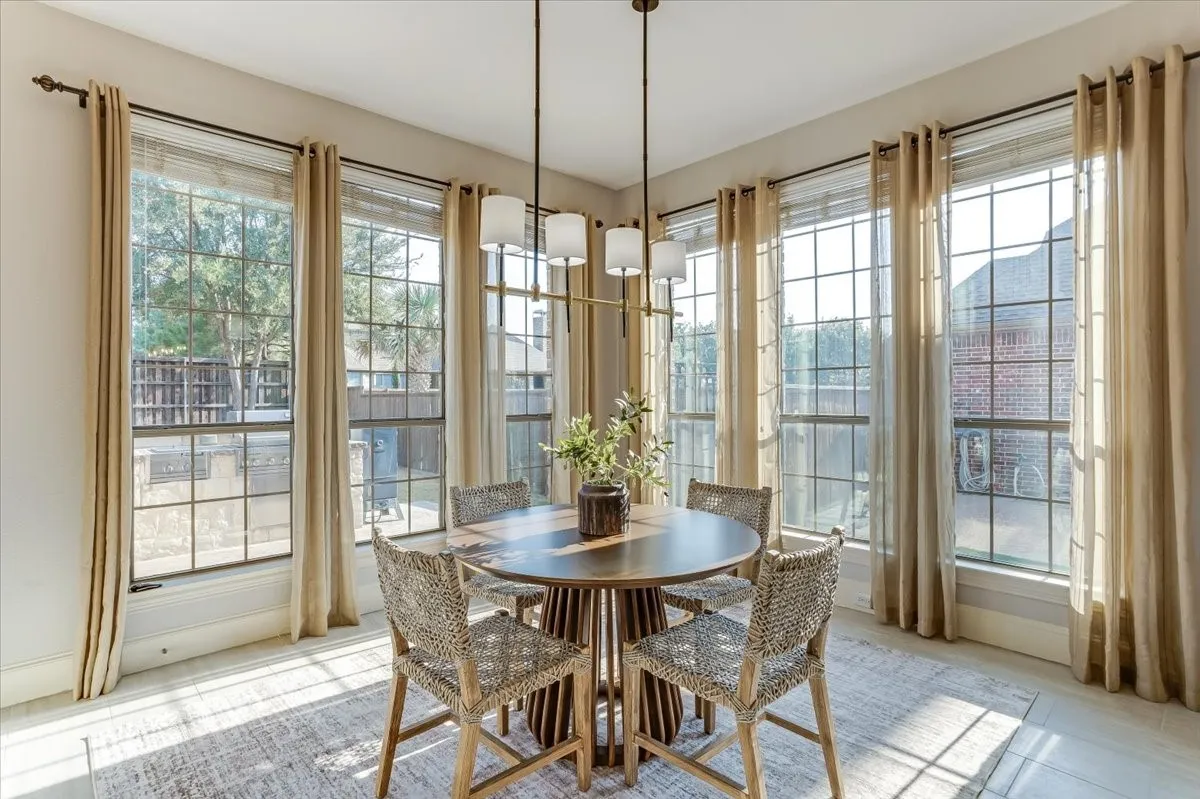 Expansive window arrangement with grid panes, a modern linear chandelier, and light-toned flooring