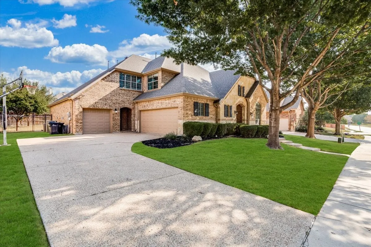 Brick and stone facade with dark shutters, dual garage doors, and a concrete driveway