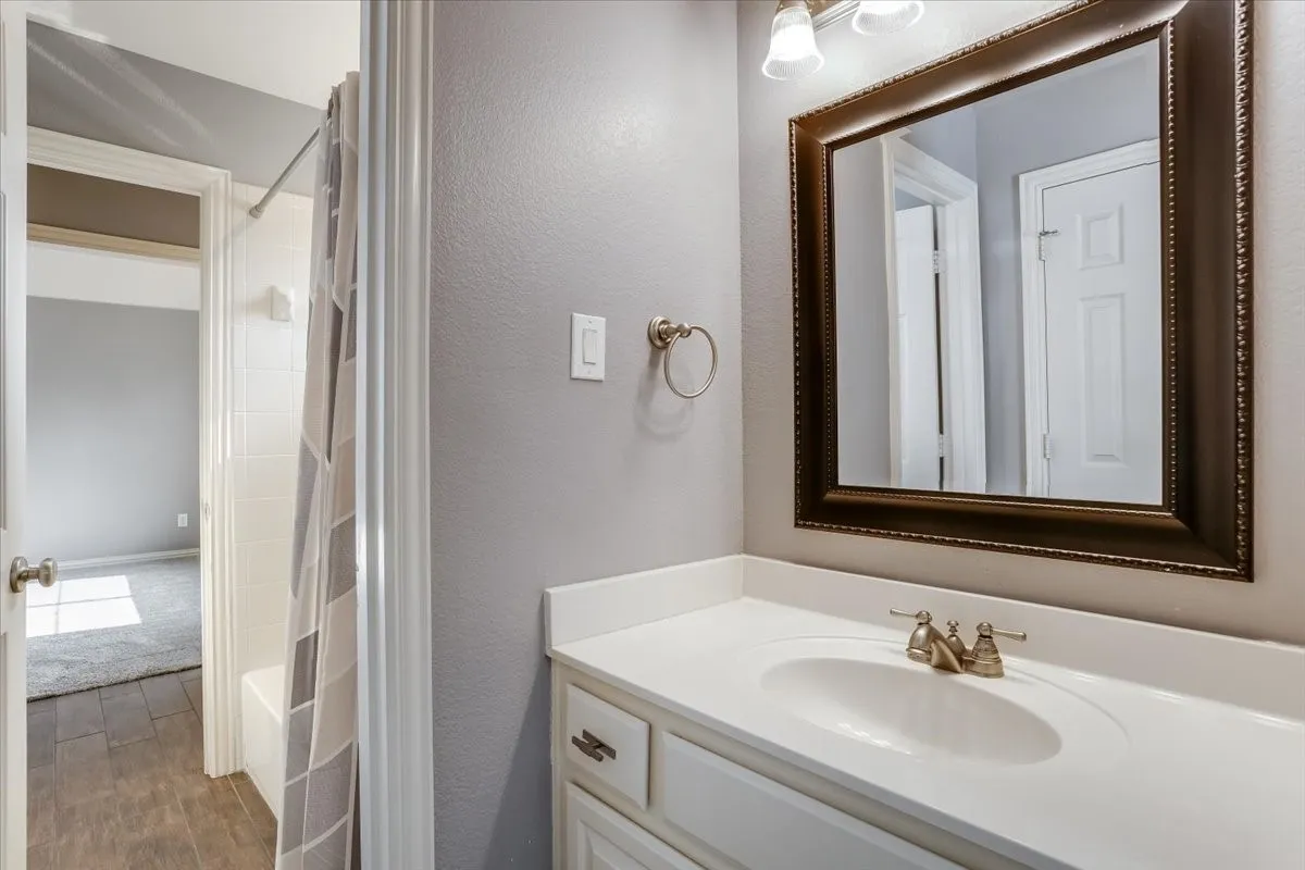 Vanity with integrated sink, bronze-finish faucet, and framed mirror
