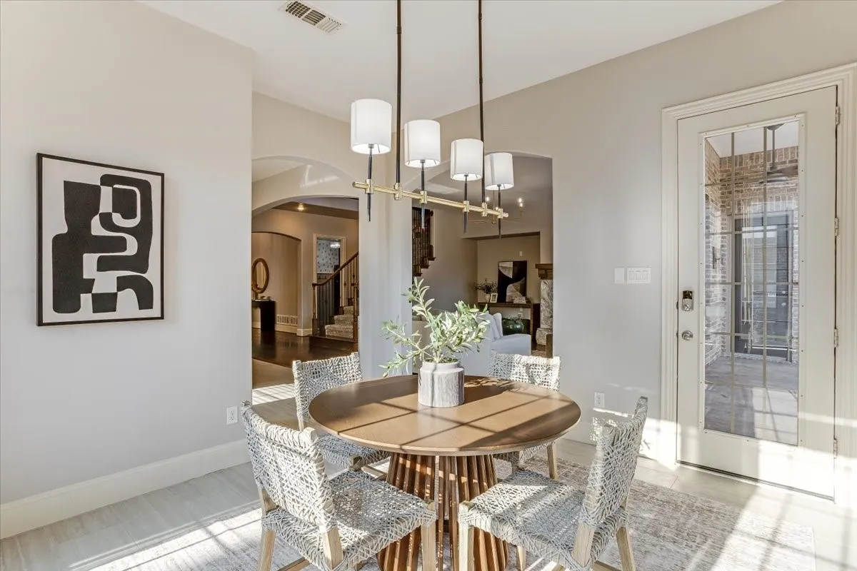 Arched doorways, wood-finish flooring, a contemporary linear chandelier, and a glass-paneled exterior door