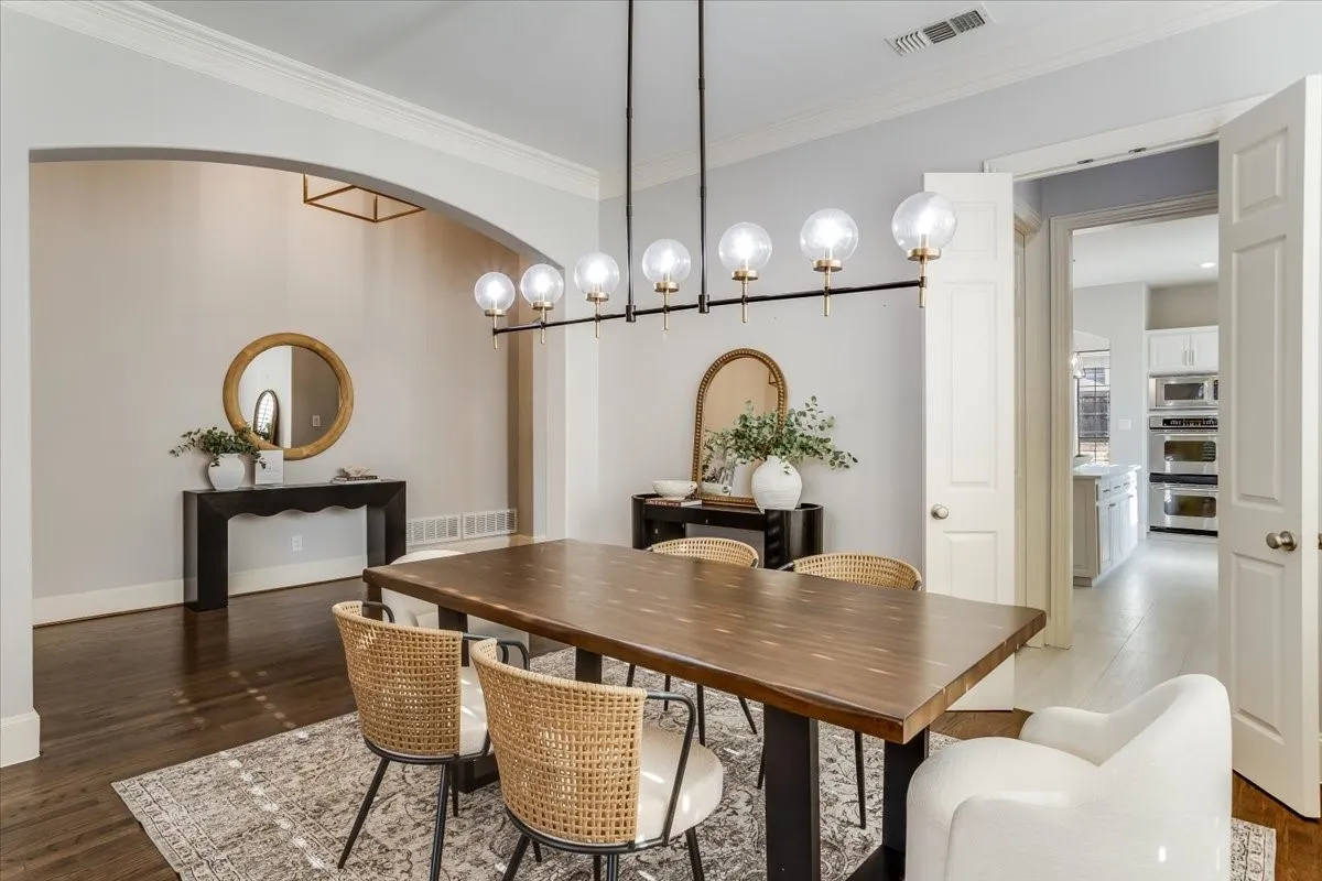 Arched entryway with crown molding, dark wood-finish flooring, and a modern linear chandelier