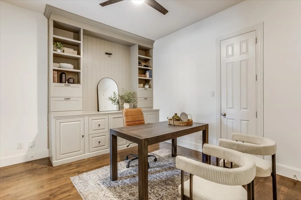Built-in cabinetry with shelving and drawers, wood-finish flooring, and a ceiling fan