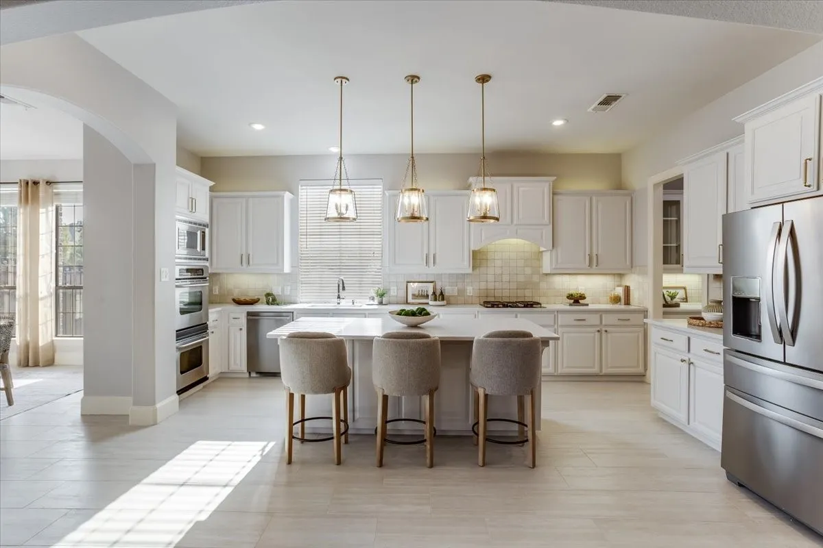 Kitchen featuring light wood-finish flooring, white cabinetry, stainless steel appliances, a center island with pendant lighting, and an arched entryway