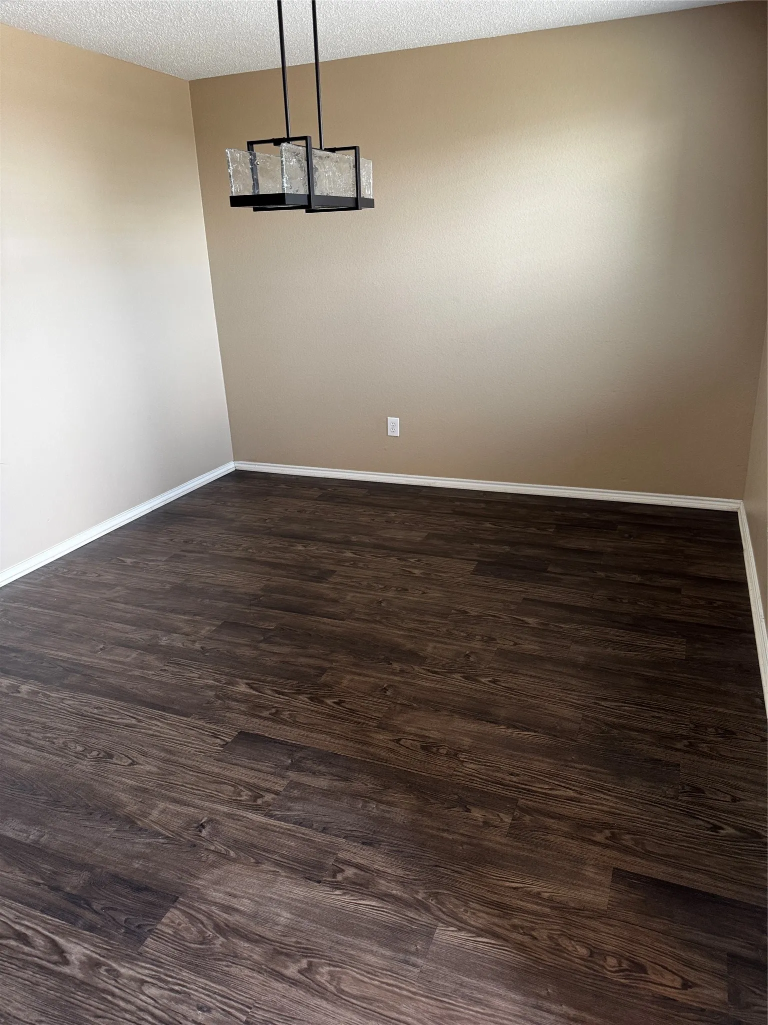 Wood-finish flooring with baseboard trim, textured ceilings, and a contemporary multi-bulb light fixture
