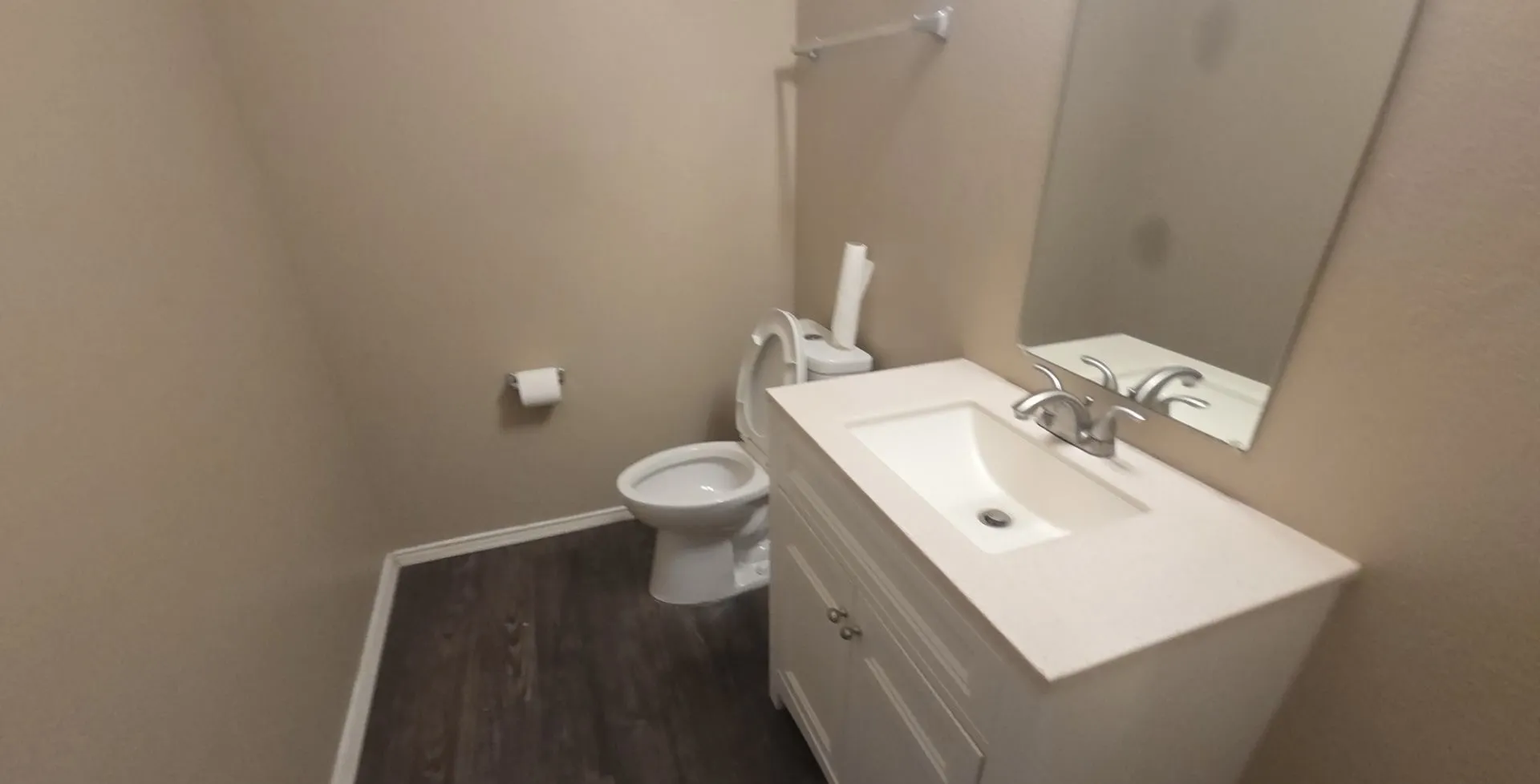 White vanity with integrated sink, brushed nickel faucet, wall-mounted mirror, and wood-finish​​‌​​​​‌​​‌‌​‌‌​​​‌‌​‌​‌​‌​​​‌​​ flooring