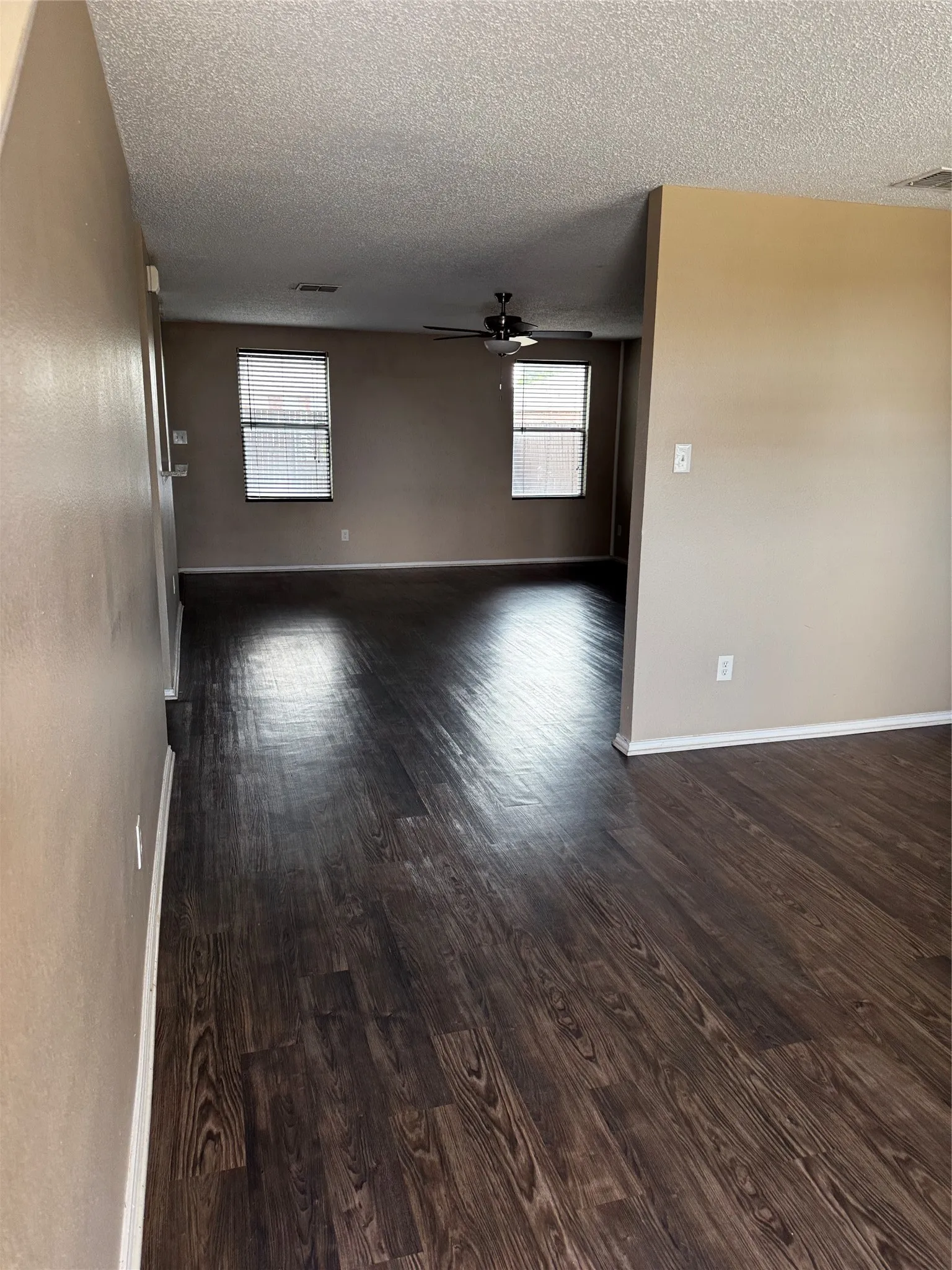 Wood-finish flooring throughout, neutral painted walls, and ceiling fan in living space