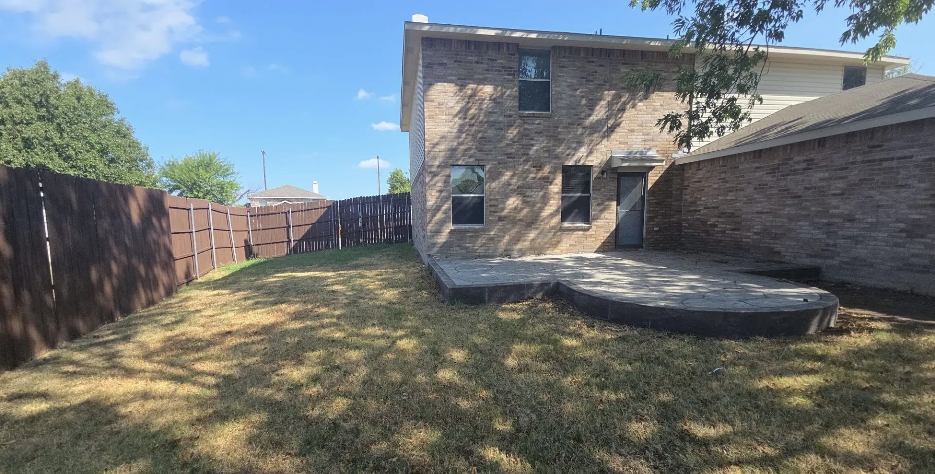 Expansive outdoor patio with a curved, multi-level design, complemented by a fully fenced perimeter