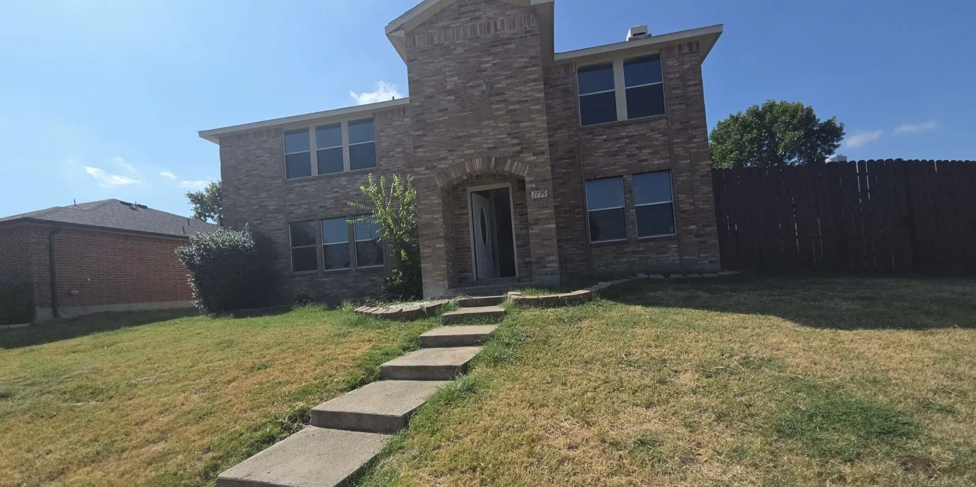 Brick exterior with a prominent arched entry, multi-pane windows, and a segmented front walkway