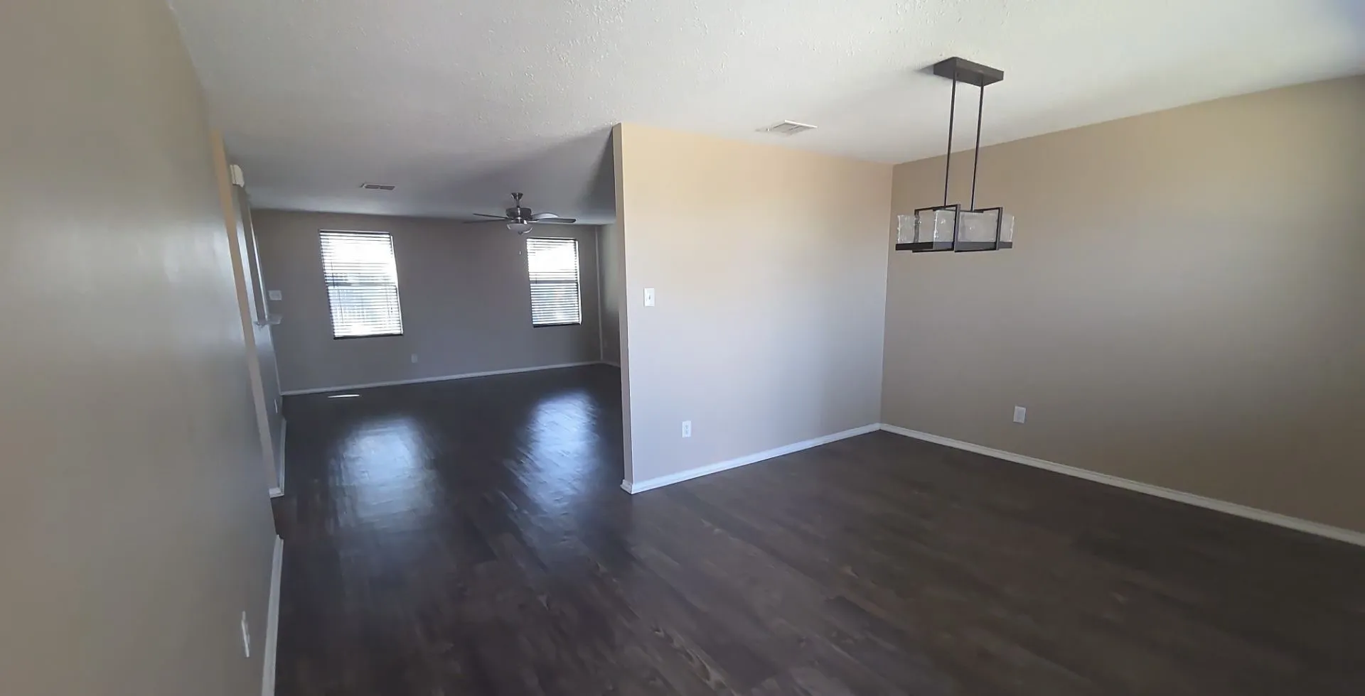 Wood-finish flooring throughout, contemporary chandelier, ceiling fan, and multiple windows providing natural light
